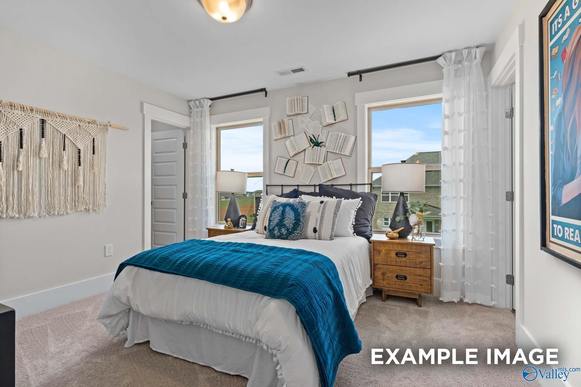 Bright bedroom with blue accents, wood nightstand, and macrame wall decor in Davidson Homes Chelsea A plan, Toney, Alabama