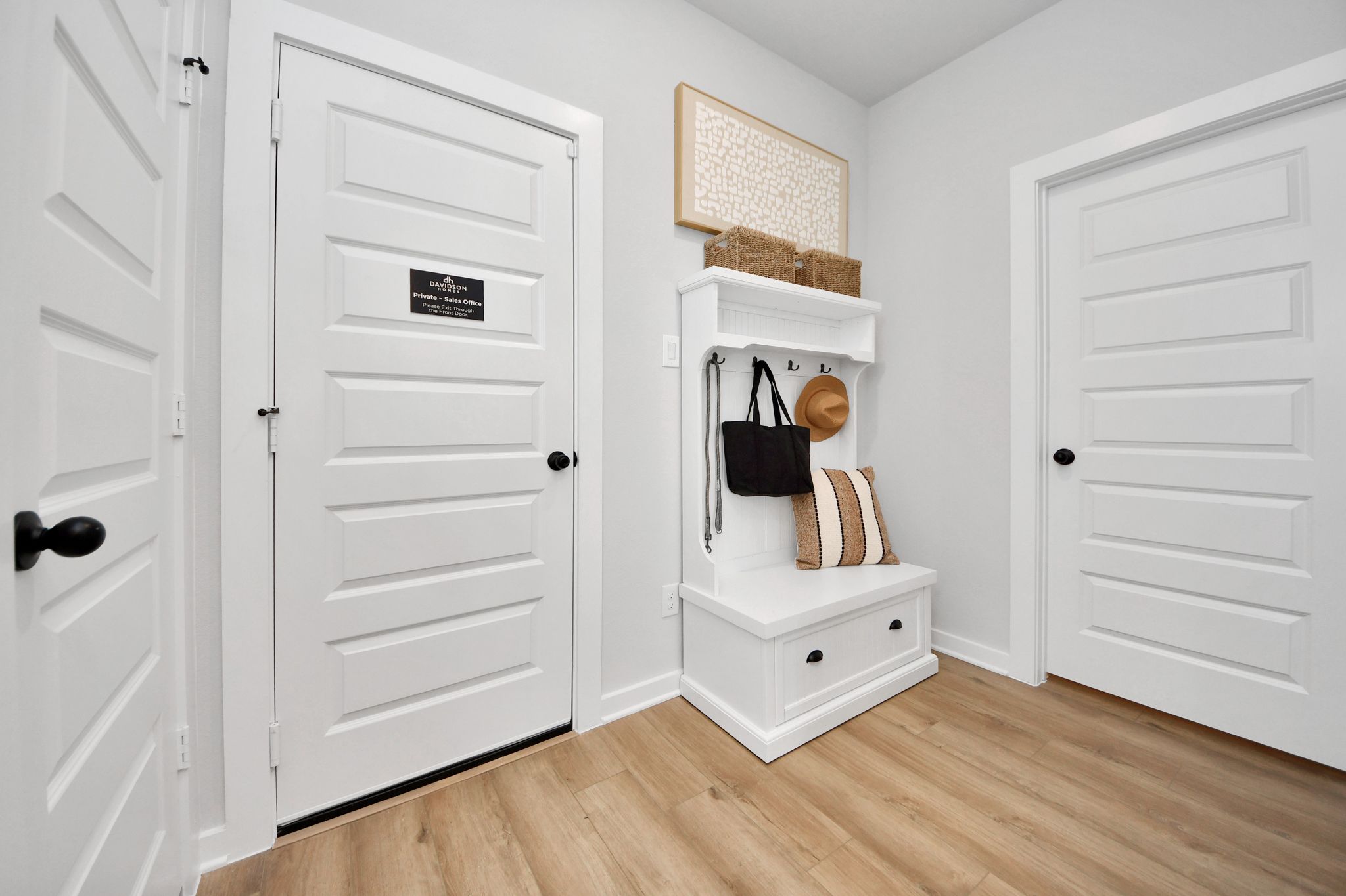White mudroom bench with coat hooks and storage at Robins Landing in Houston, Texas by Davidson Homes