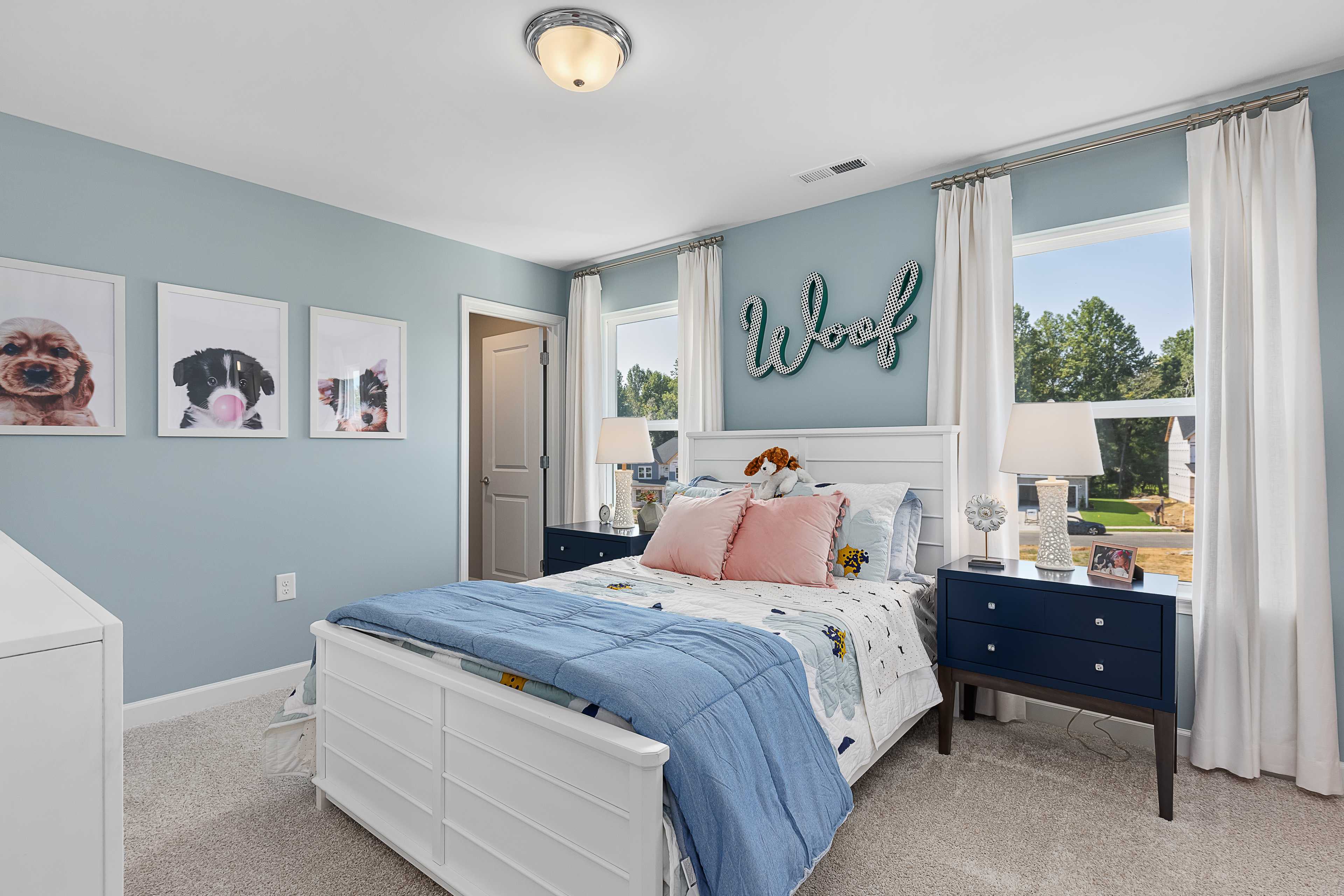 Dog-themed kids' bedroom at Woodland Crossing in Zebulon, NC with light blue walls, white bed and window views