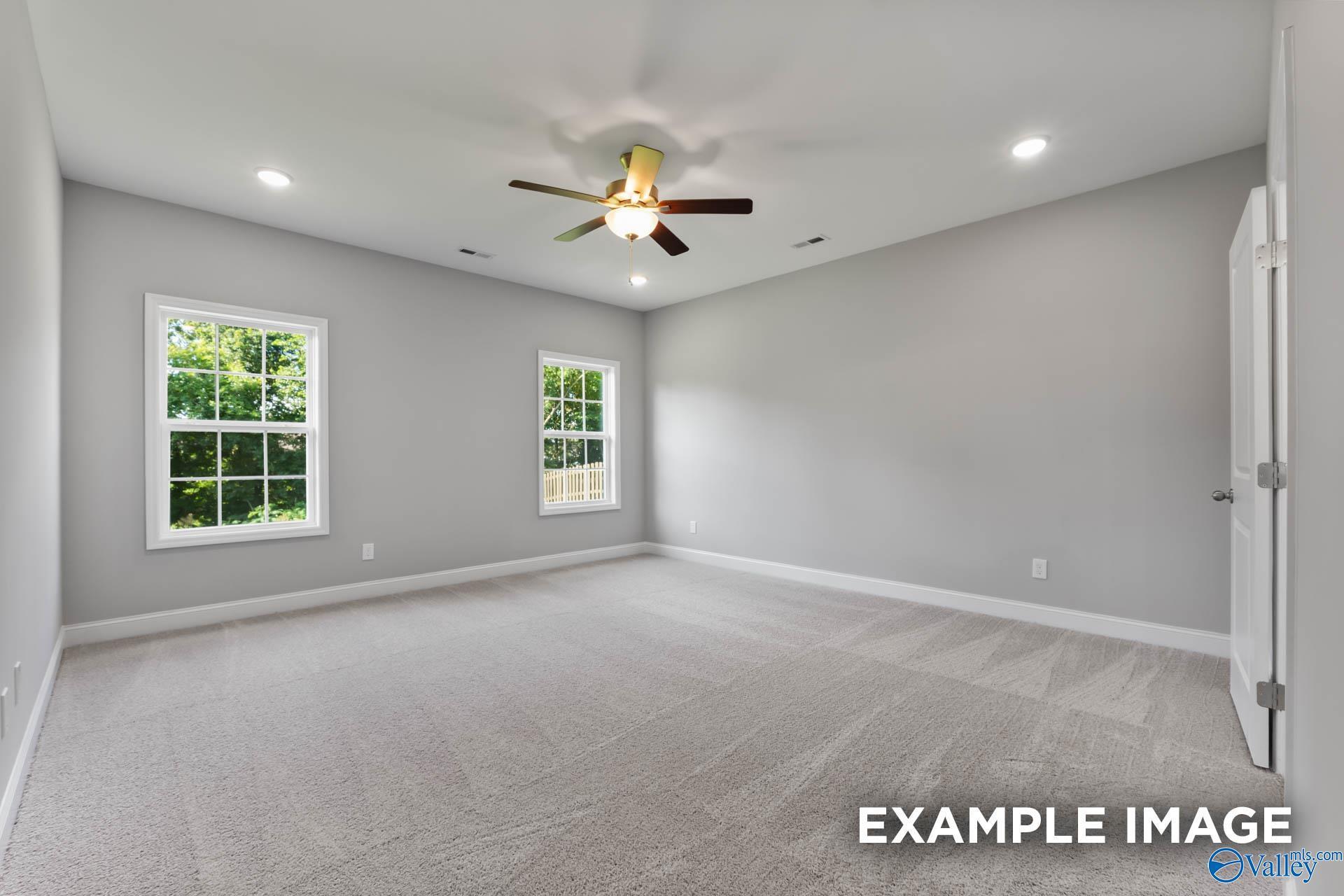 Bright secondary bedroom with ceiling fan, large windows, and neutral gray walls in Davidson Homes The Rockford, Madison AL