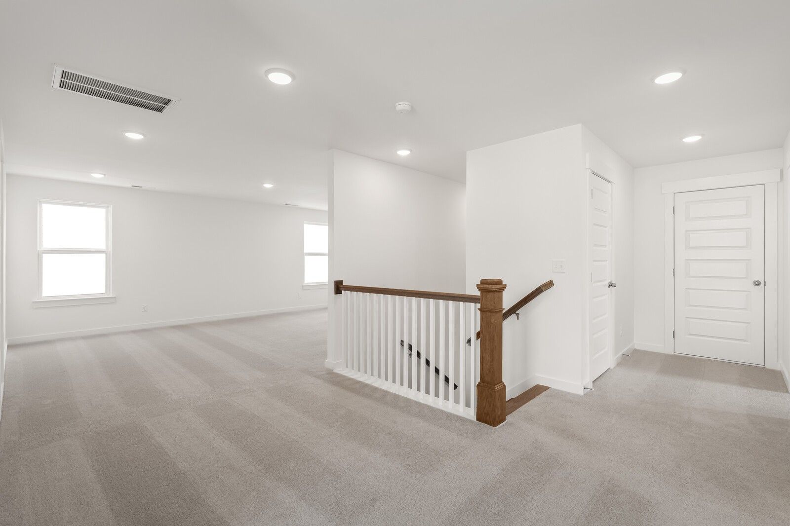 Spacious upstairs hallway with wooden staircase, large windows, and carpeted floors in Davidson Homes The Ash A, Gallatin, TN