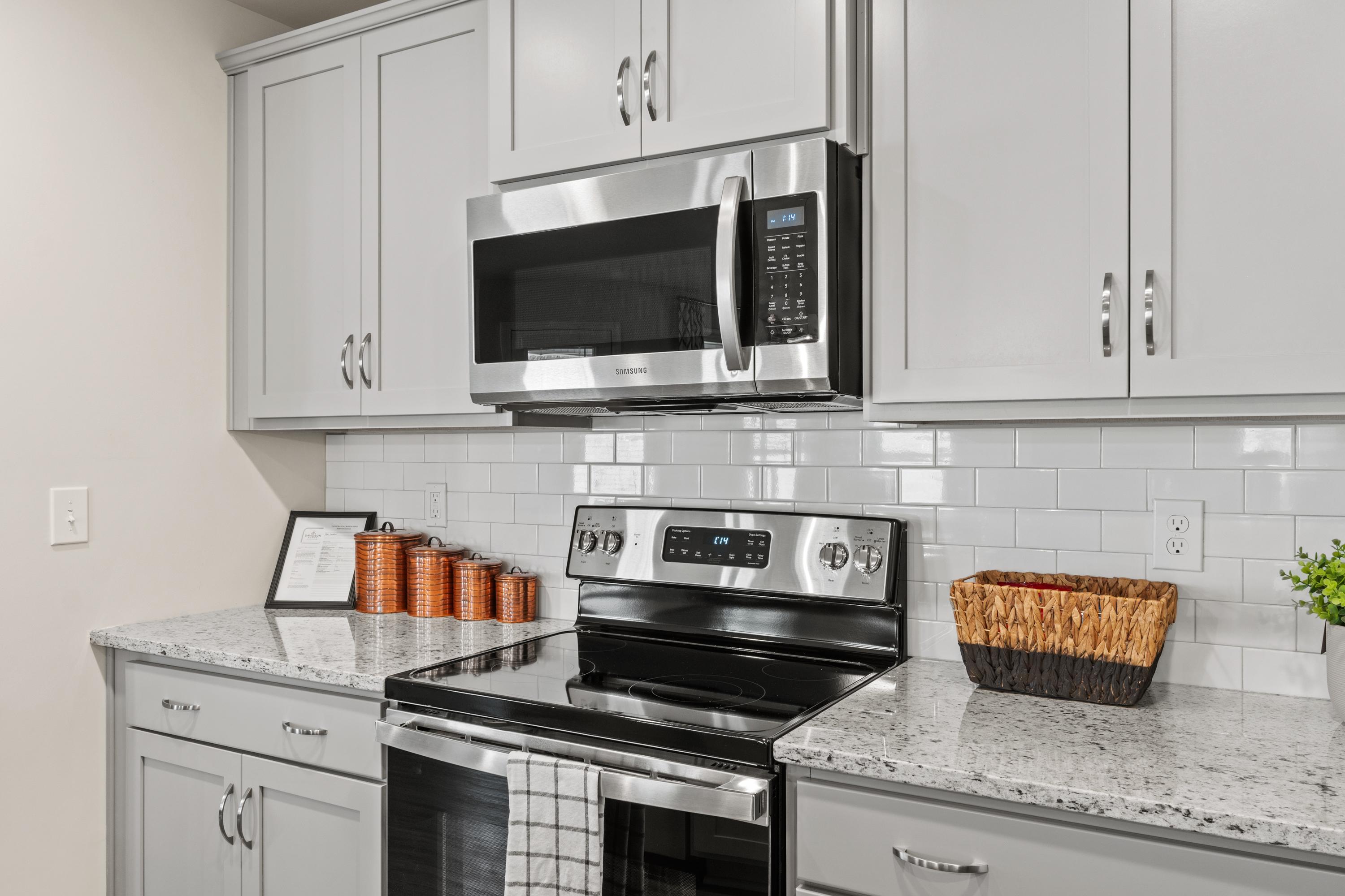 Modern kitchen in Berry Cove home, New Market AL with white cabinets, stainless steel appliances, subway tile backsplash, and quartz counters