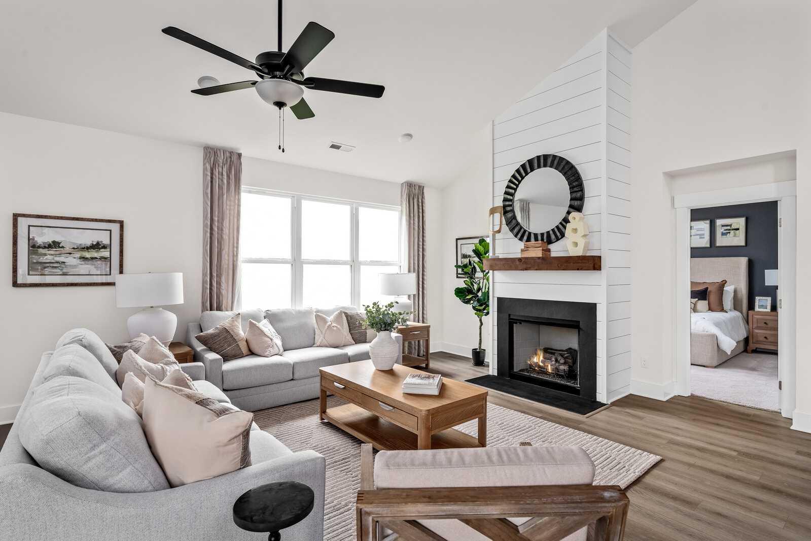 Spacious living room at Woods Crossing in Gallatin TN with gray sofa, gas fireplace, shiplap wall, and hardwood floors