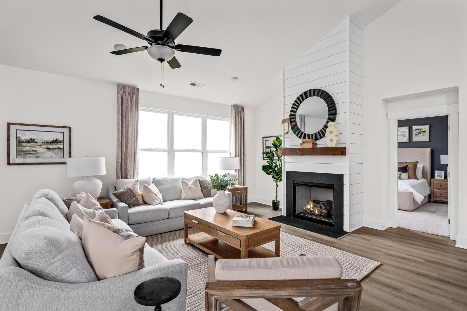 Spacious living room at Woods Crossing in Gallatin TN with gray sofa, gas fireplace, shiplap wall, and hardwood floors