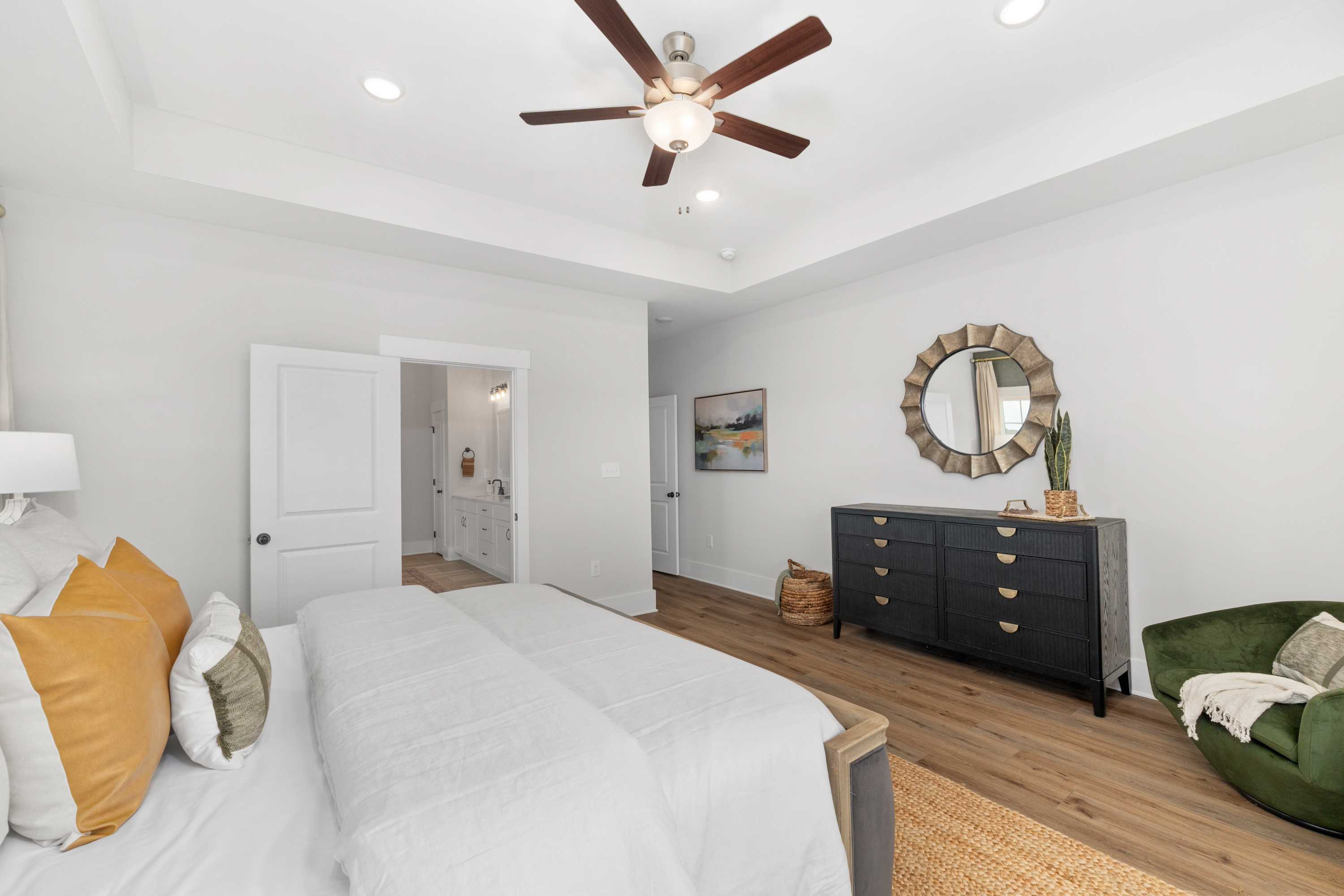 Spacious master bedroom in Briercreek, Meridianville AL by Davidson Homes with king bed, ceiling fan, hardwood floors, and en-suite bath