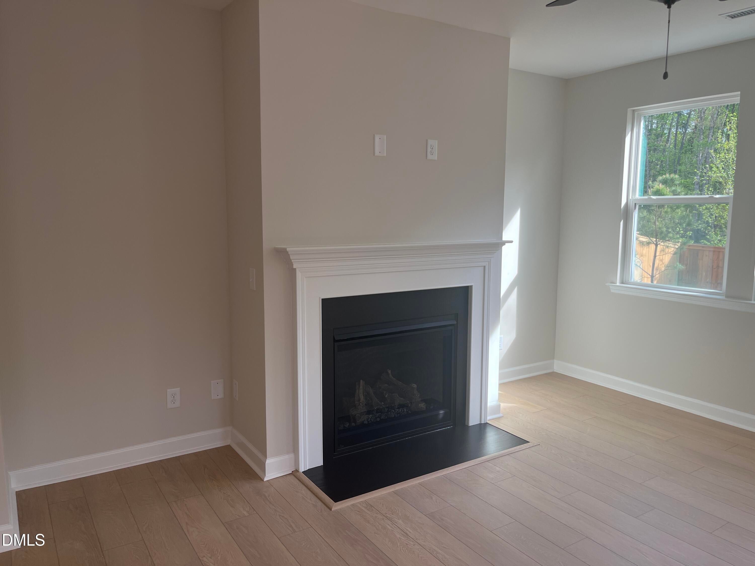 Cozy gas fireplace with white mantel, beige walls, hardwood floors in Ashport L living room, Davidson Homes, Wake Forest, NC