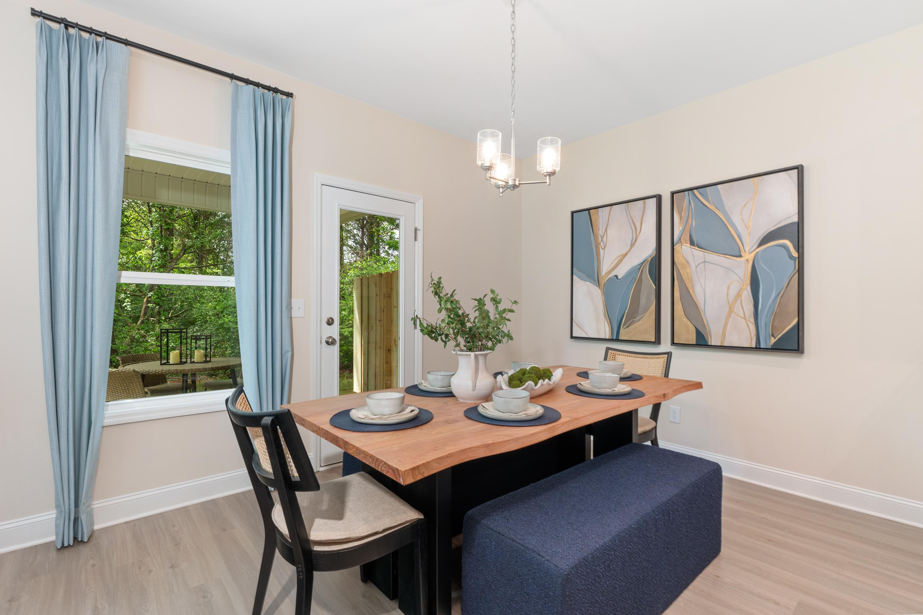 Contemporary dining room at Pavilion in Huntsville AL with rustic wood table, blue curtains, abstract art, and garden view