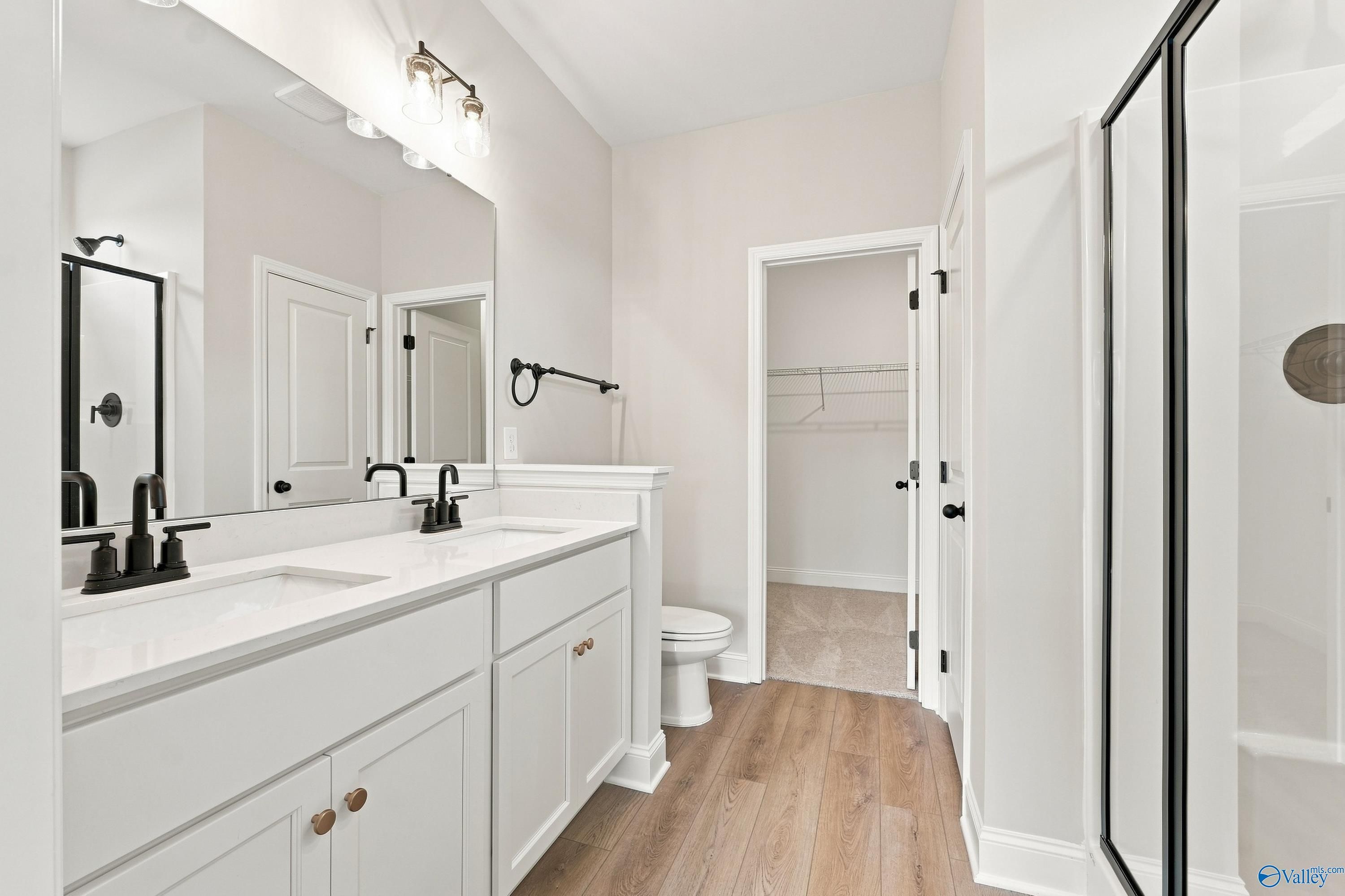 Modern master bathroom with dual vanity, walk-in closet, and glass shower in The Asheville E home, Forest Glen, Alabama.