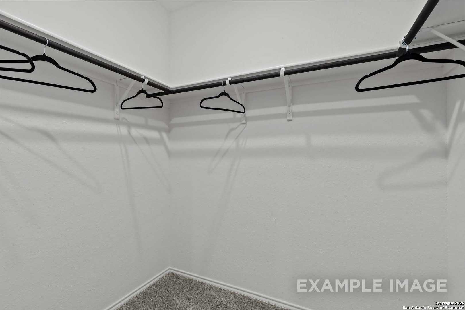 Spacious walk-in closet with double hanging rods and white plastic hangers in Davidson Homes The Douglas C, Seguin, Texas