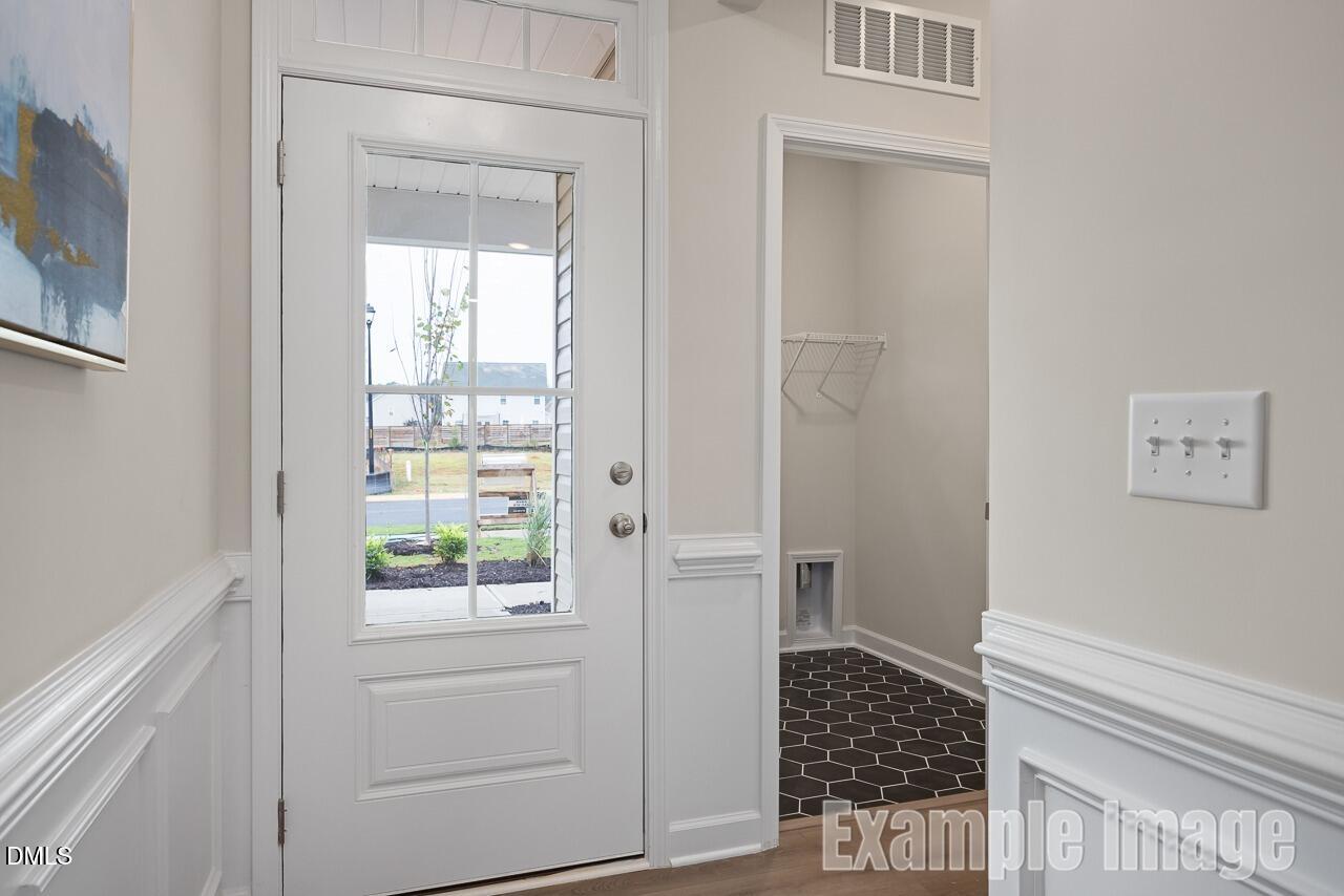 Bright entryway with glass-paneled white door, coat closet, pet door in Davidson Homes The Carter C, Gregory Village, Lillington, NC