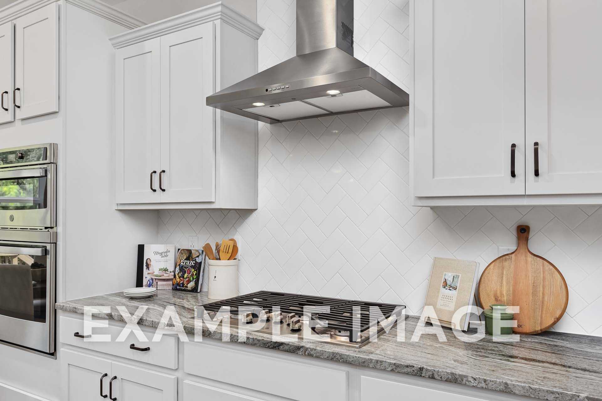 Modern kitchen in The Willow F featuring white shaker cabinets, granite counters, subway tile backsplash, and stainless steel appliances