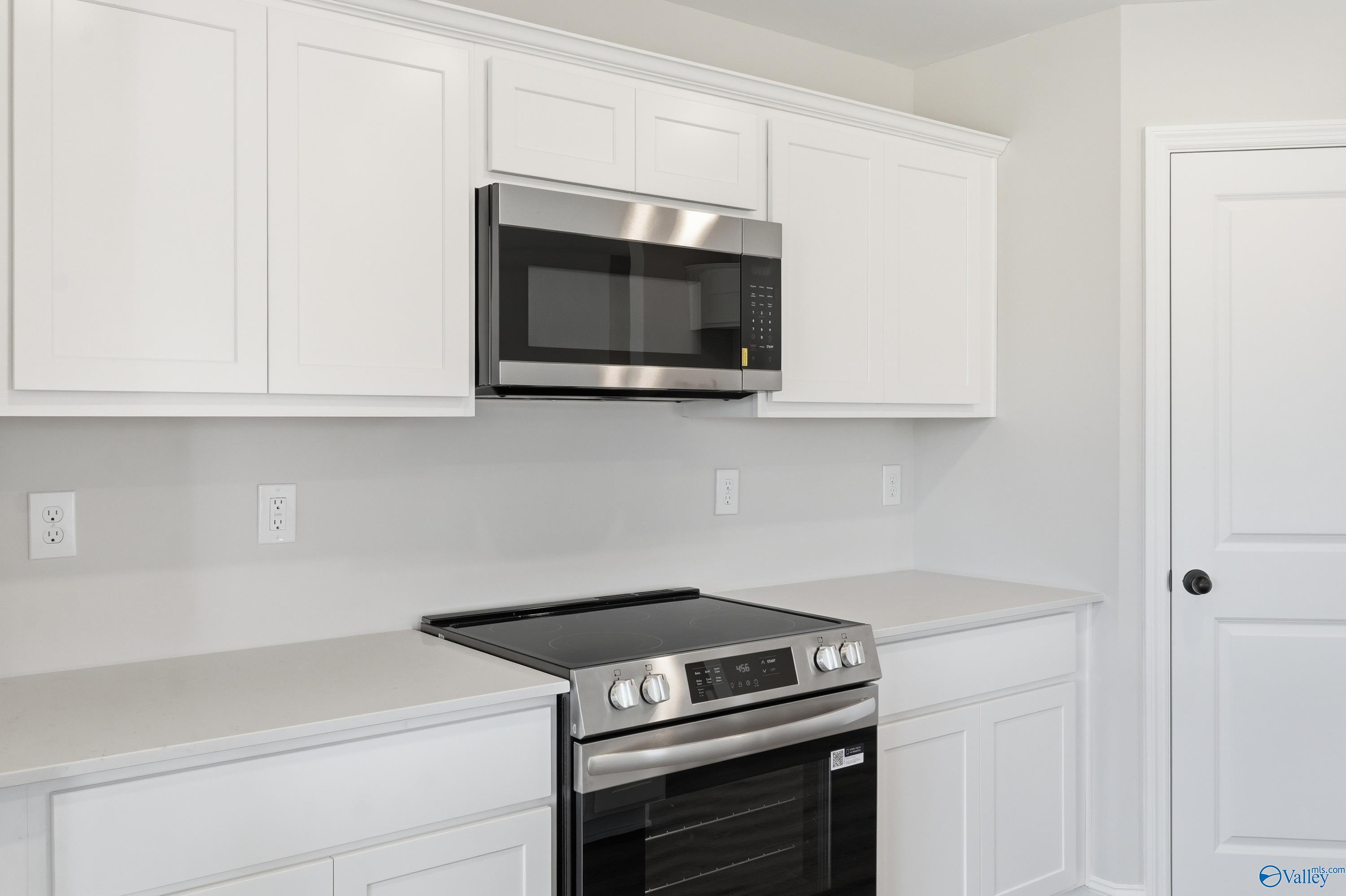 Modern kitchen featuring white cabinets, stainless steel microwave over range in Davidson Homes The Franklin V, Athens, Alabama