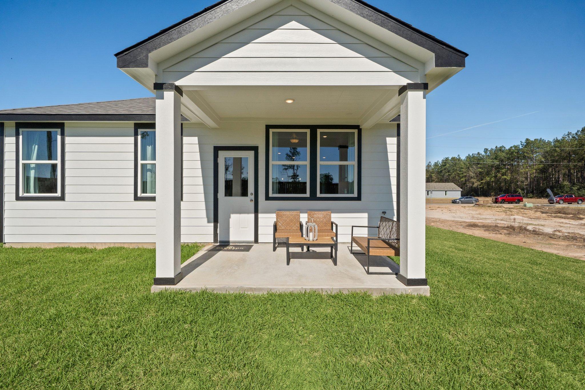 Modern white home exterior at Spring Branch Crossing in Conroe TX with covered porch, columns, and outdoor seating