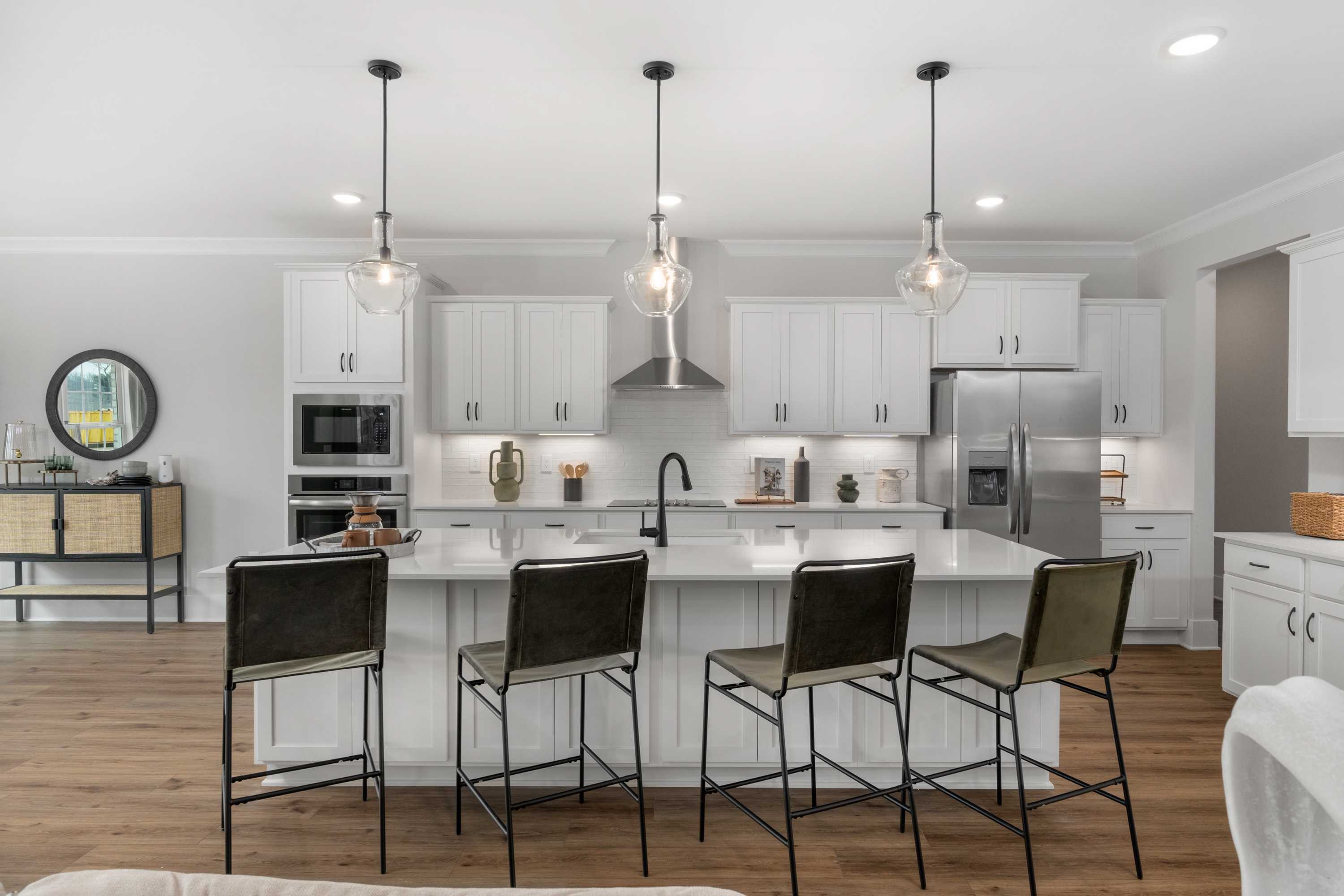 Spacious modern kitchen in Briercreek Meridianville AL with white cabinets, quartz island, pendant lights, stainless appliances