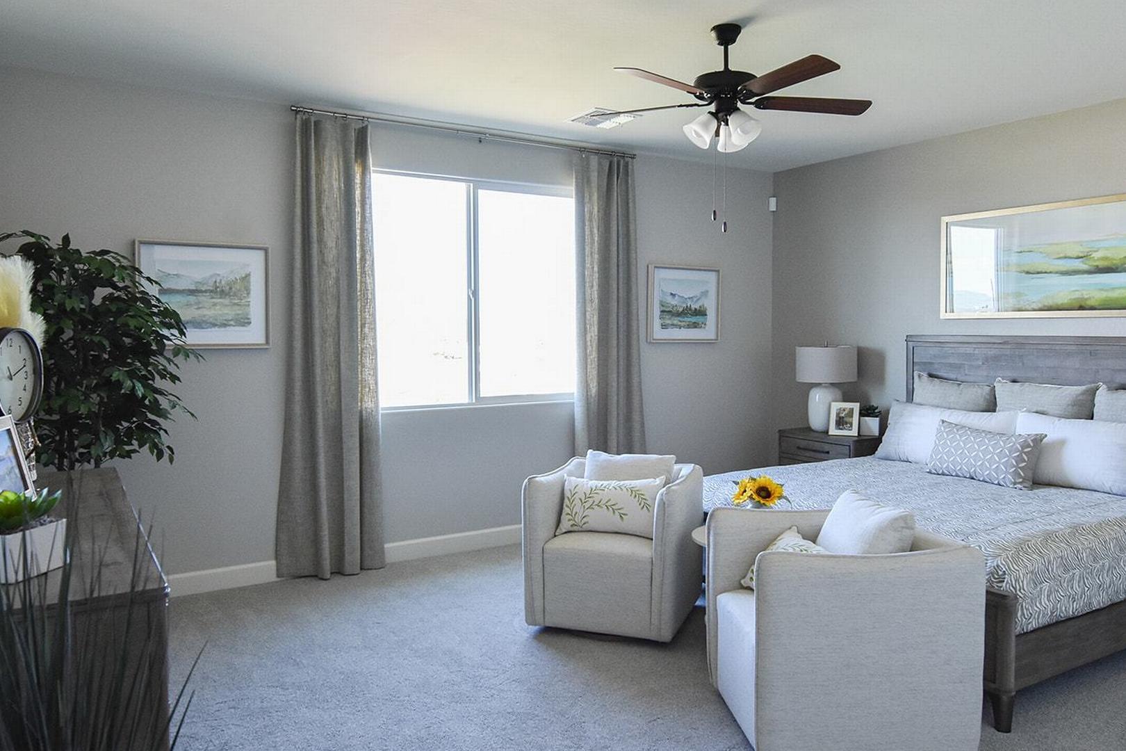 Spacious master suite in The Summit E by Evermore Homes, Prescott Valley: king bed, gray walls, ceiling fan, armchairs, artwork