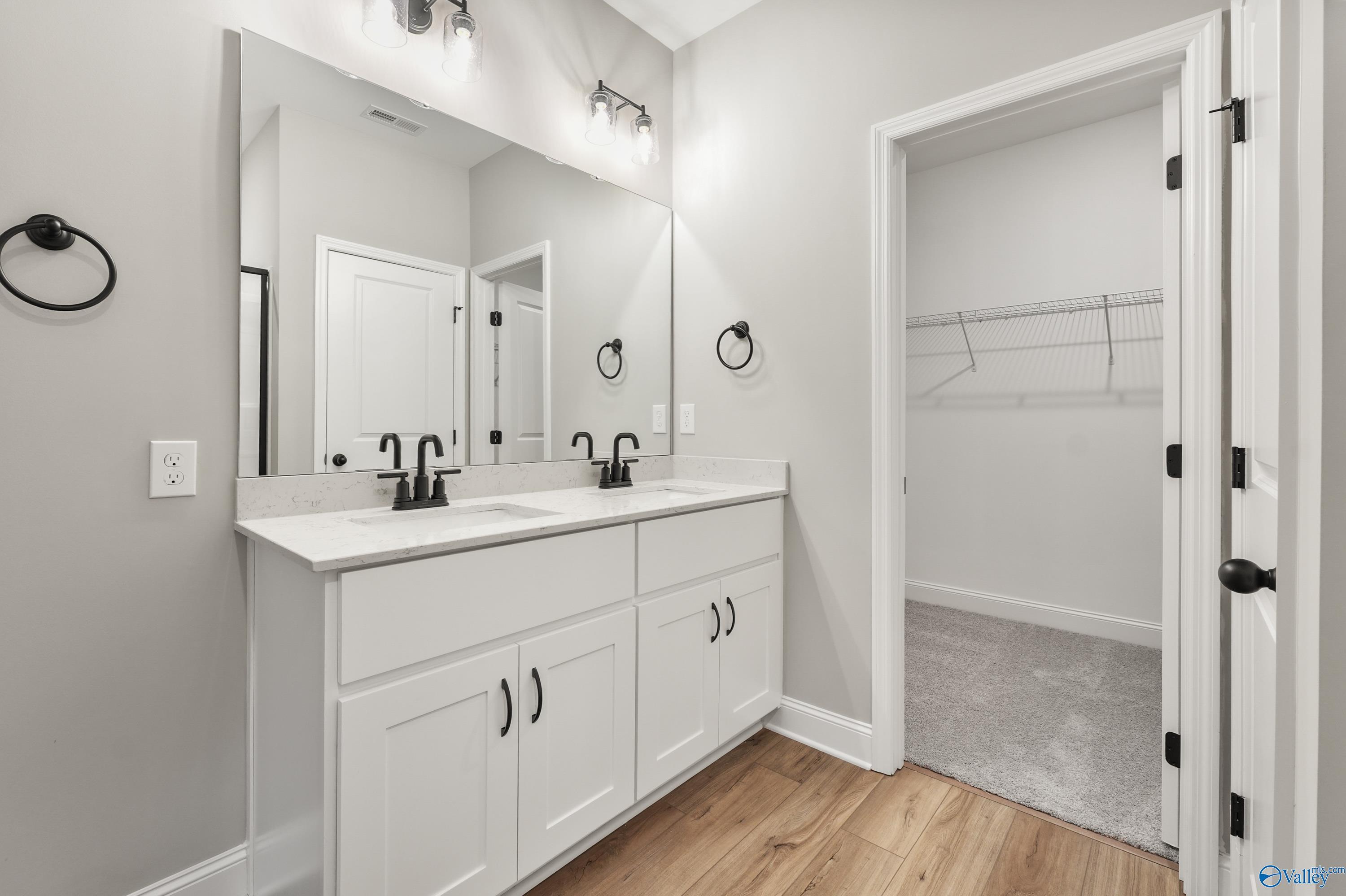 Modern master bathroom featuring double white vanity, two sinks, mirrors, and open walk-in closet in Davidson Homes The Asheville C, Meridianville, Alabama