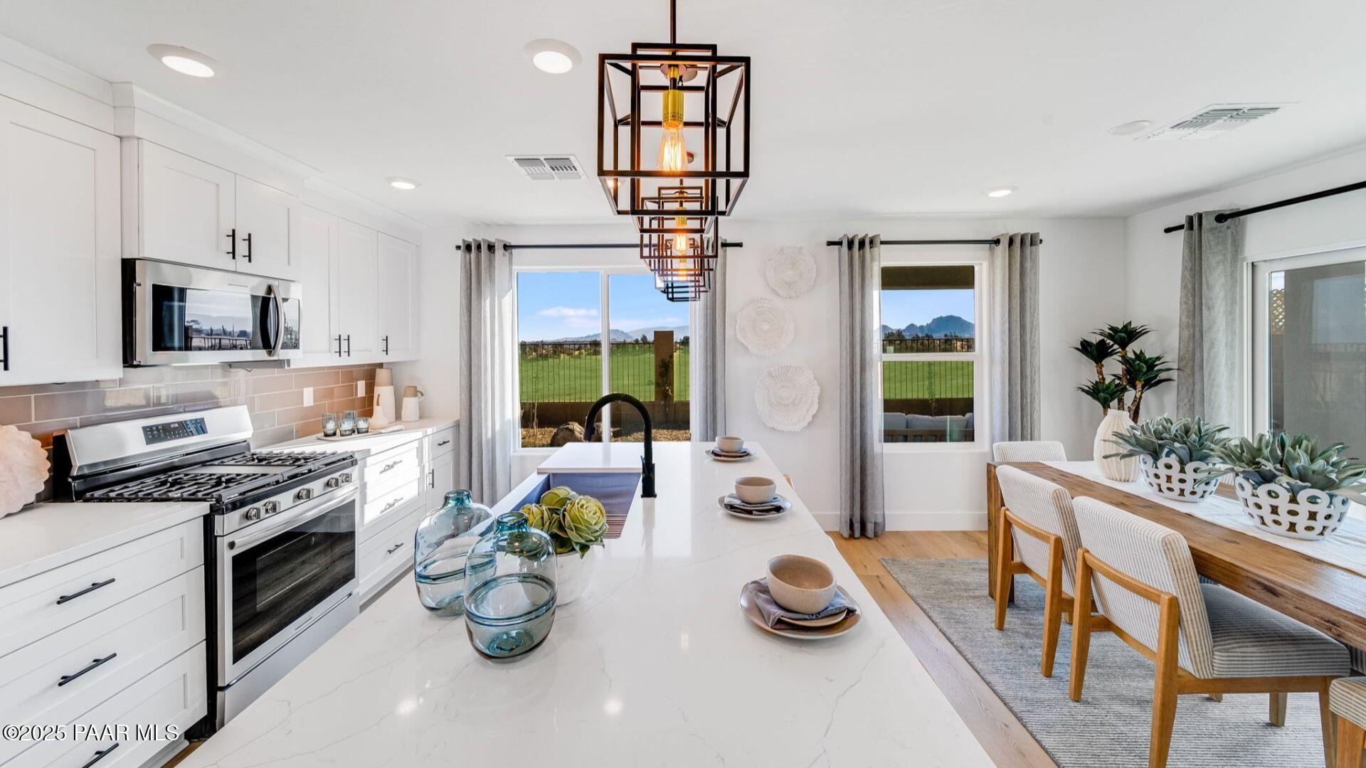 Modern open-concept kitchen with white quartz island, stainless appliances, and desert view in Davidson Homes Wilmington B, Prescott AZ