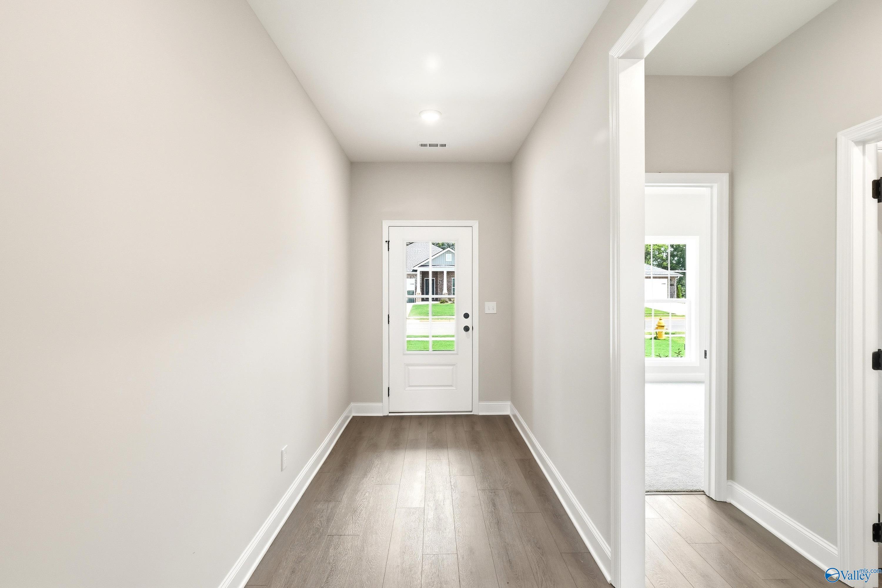 Bright foyer with wood-look flooring leads to front door in The Daphne floor plan by Davidson Homes in Meridianville, AL.