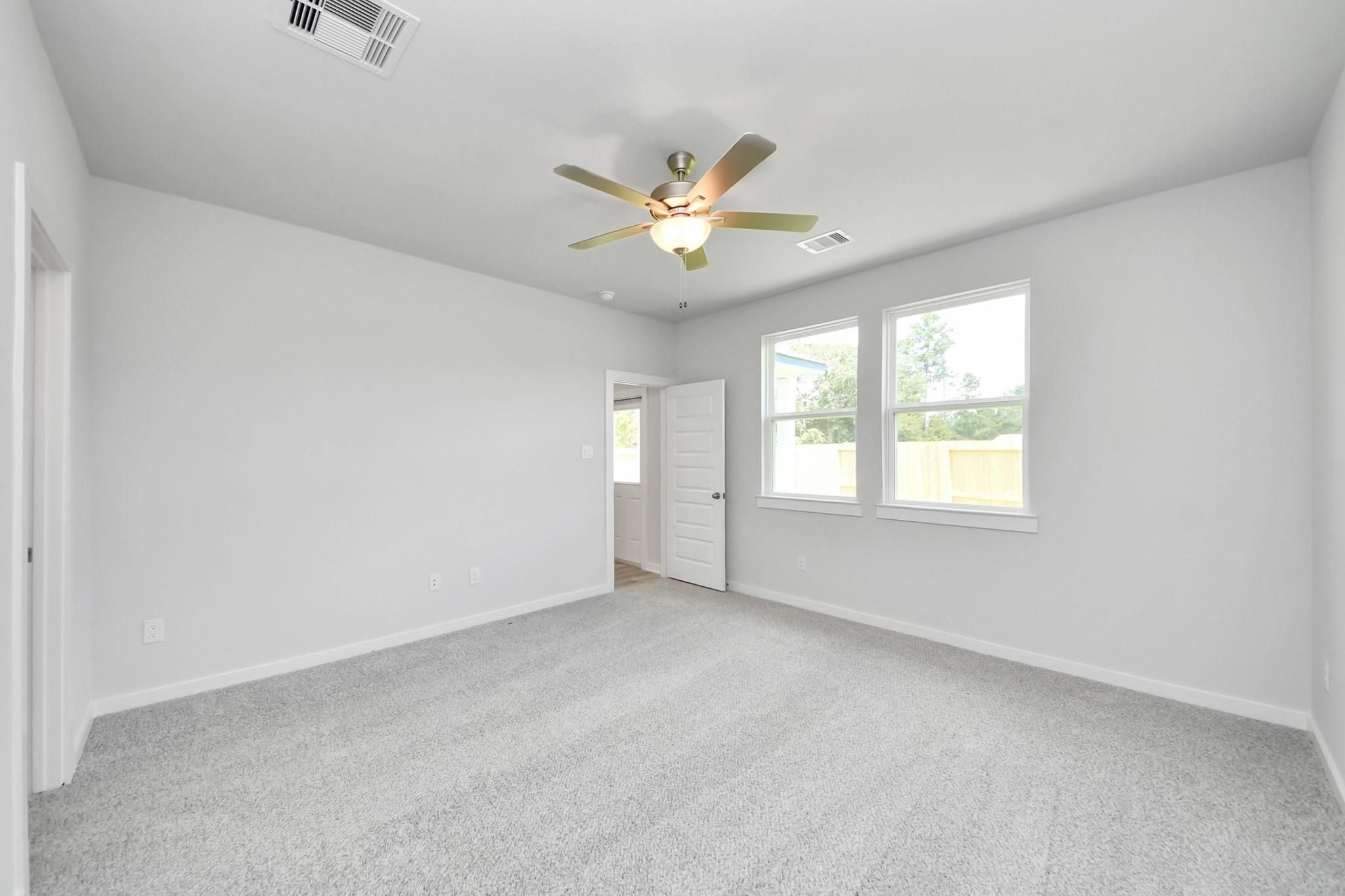 Spacious carpeted bedroom with ceiling fan in The Sabine F floor plan at Liberty Estates, Cleveland, Texas.