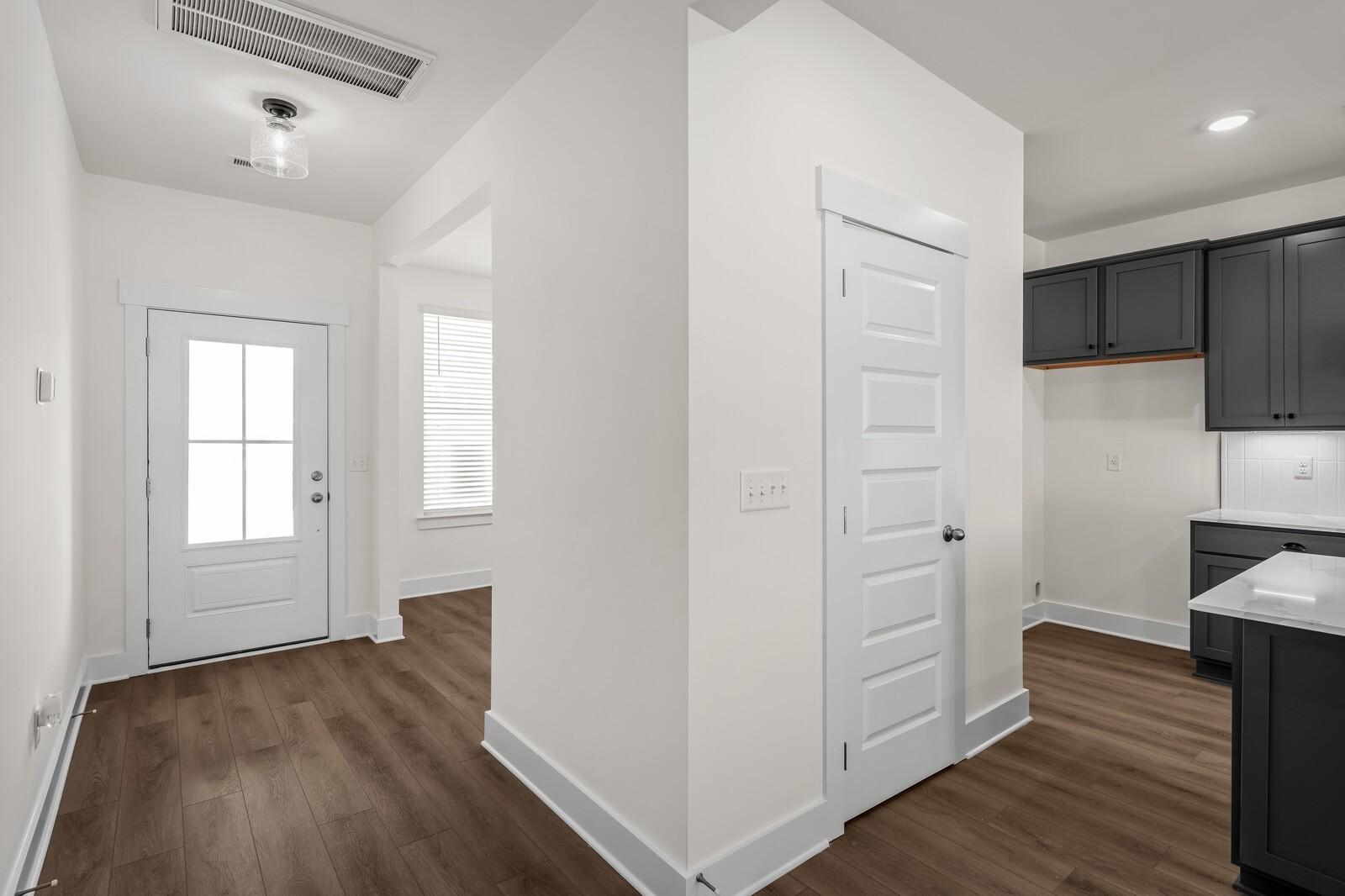 Modern entryway featuring white door and wood-style flooring in The Willow floor plan at Woods Crossing, Gallatin, TN.