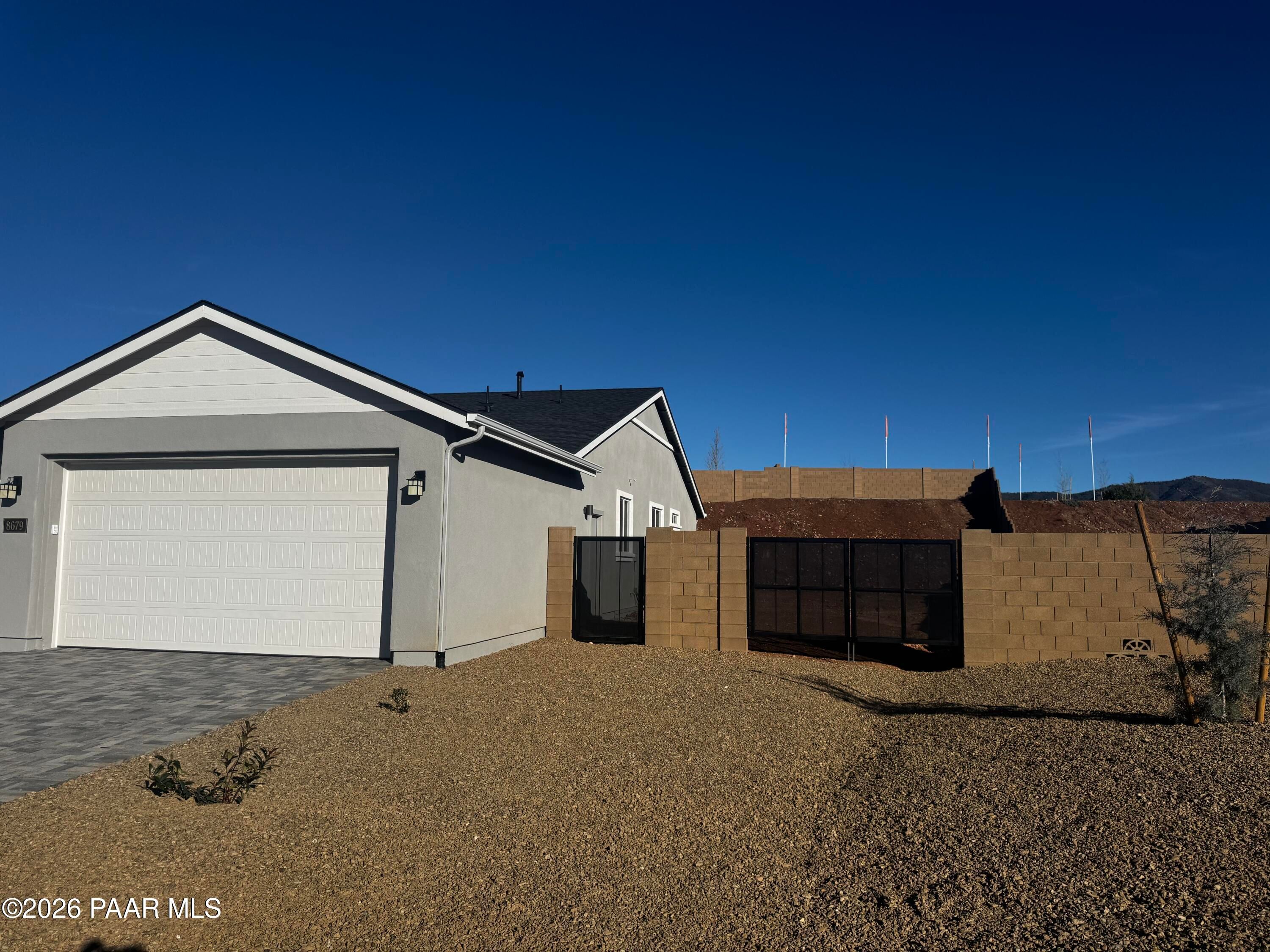 Modern single-story home exterior with open 3-car garage, block fencing, desert landscape in Morningstar, Prescott Valley, Arizona
