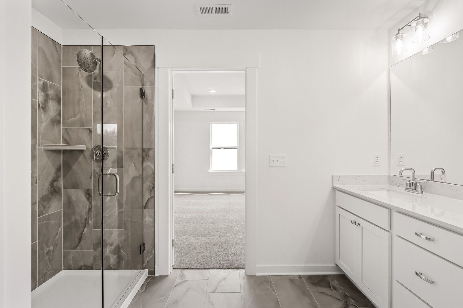 Modern master bath with frameless glass shower, gray tile, double white vanity in Davidson Homes The Willow D, Mt. Juliet, TN