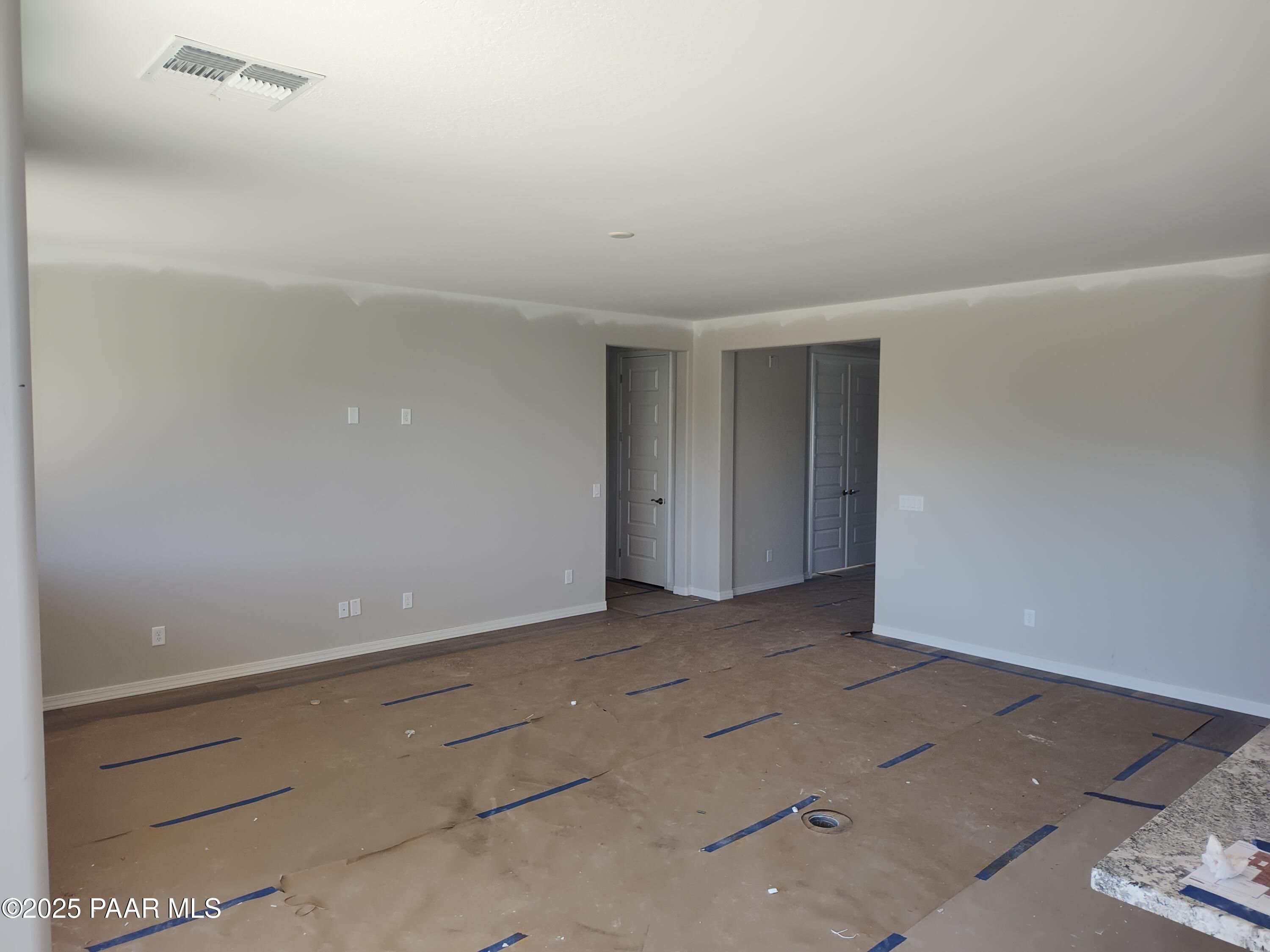 Empty bedroom with neutral beige walls, double doors, electrical outlets, and protective blue flooring in Davidson Homes The Harmony A, Prescott Valley