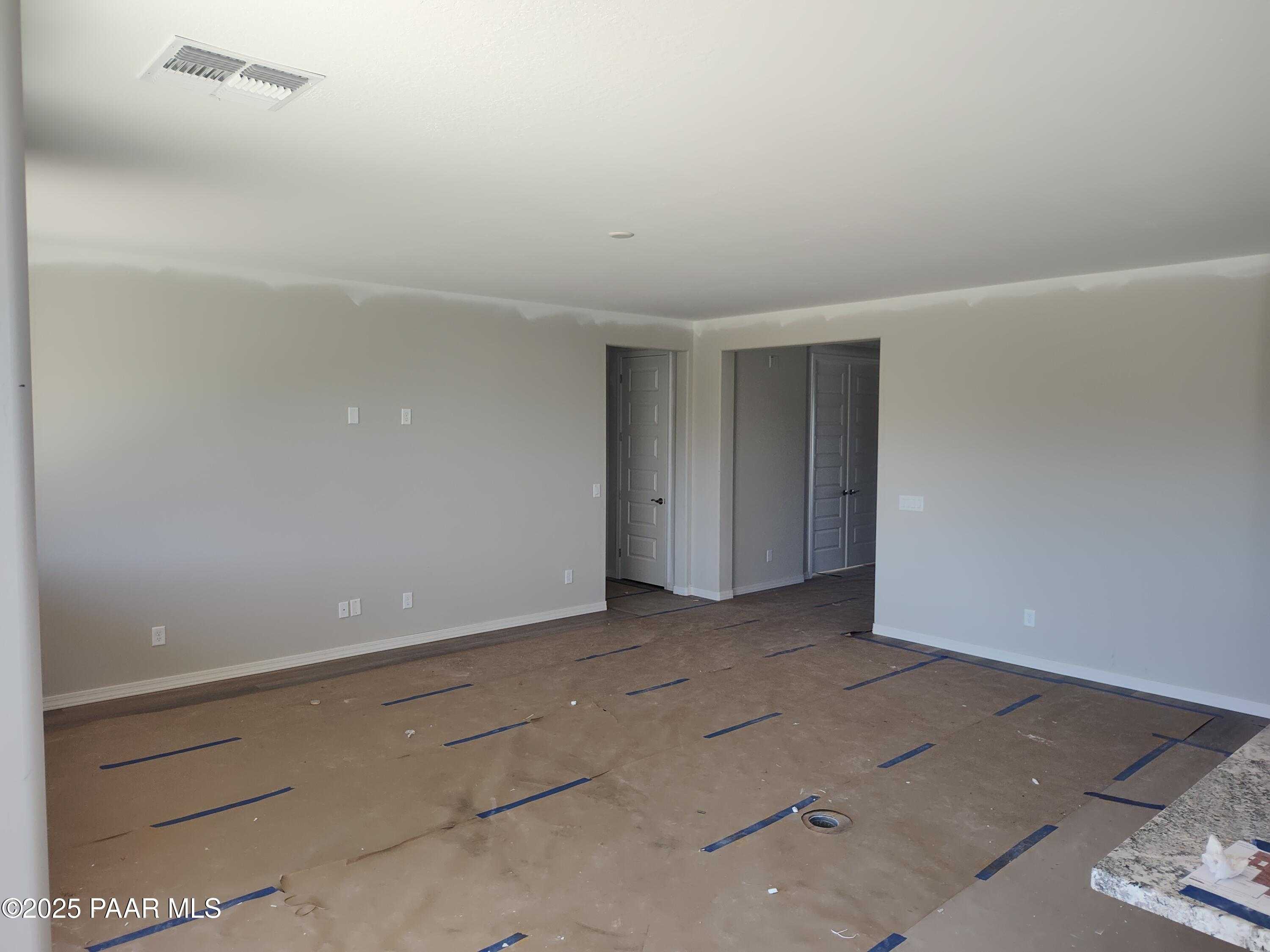 Spacious empty master bedroom with light walls, double closet doors, en-suite access, blue protective flooring, adjacent counter in Davidson Homes Harmony C, Prescott Valley AZ