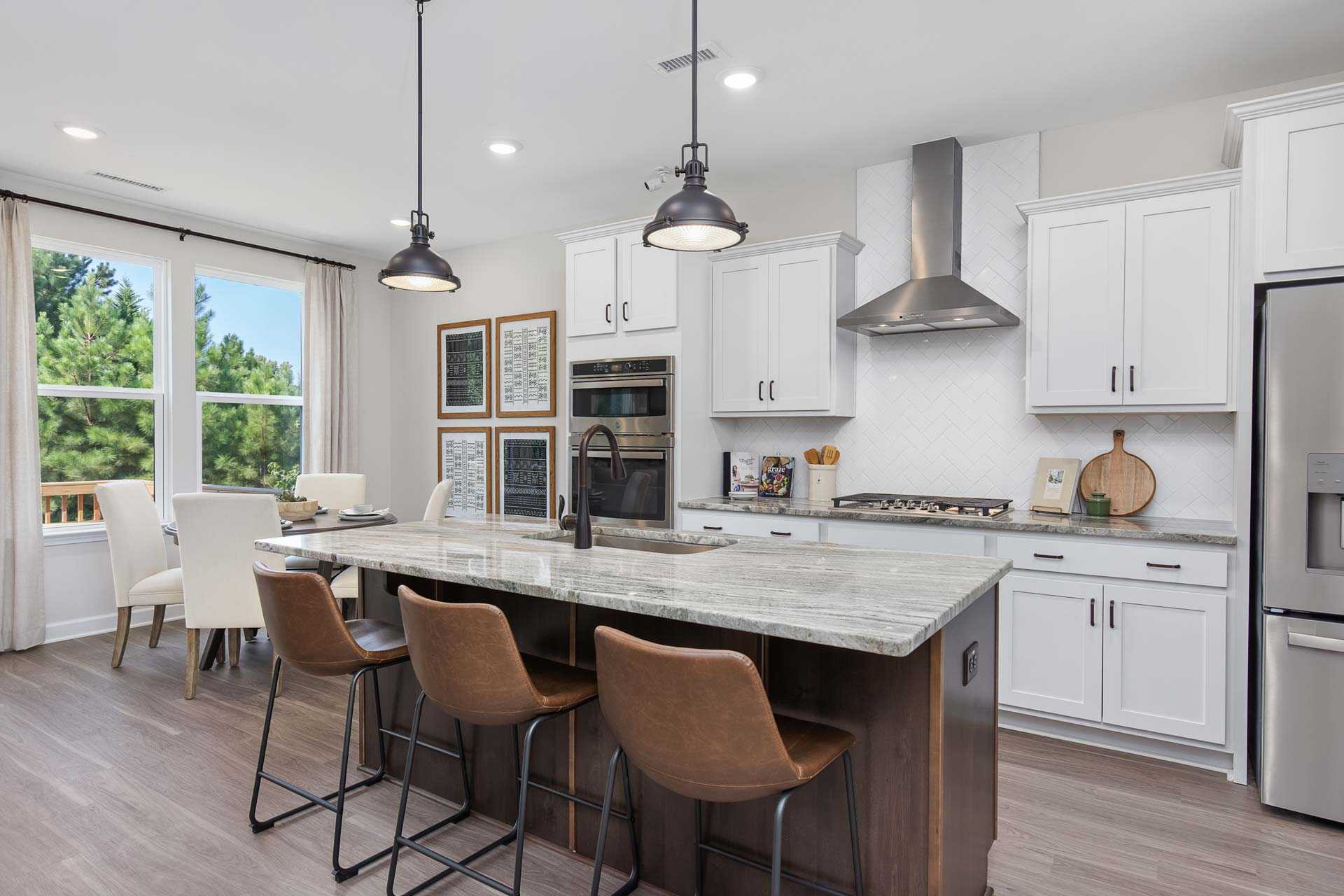 Modern kitchen at Sierra Heights in Clayton NC with white cabinets, quartz island, leather bar stools, pendant lights, and hardwood floors