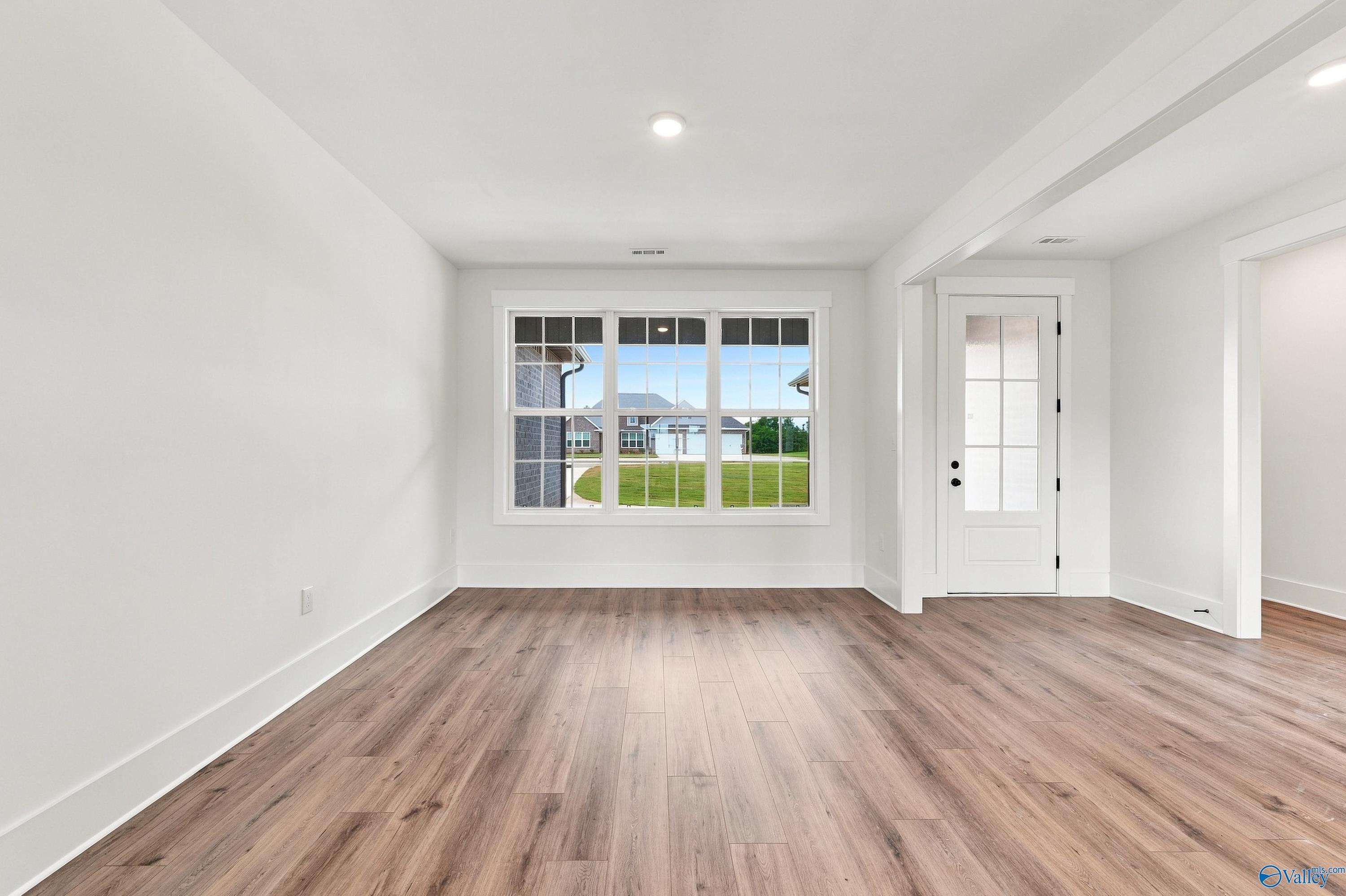 Bright empty living room with luxury vinyl plank flooring and large front windows in Davidson Homes Valencia plan, Huntsville