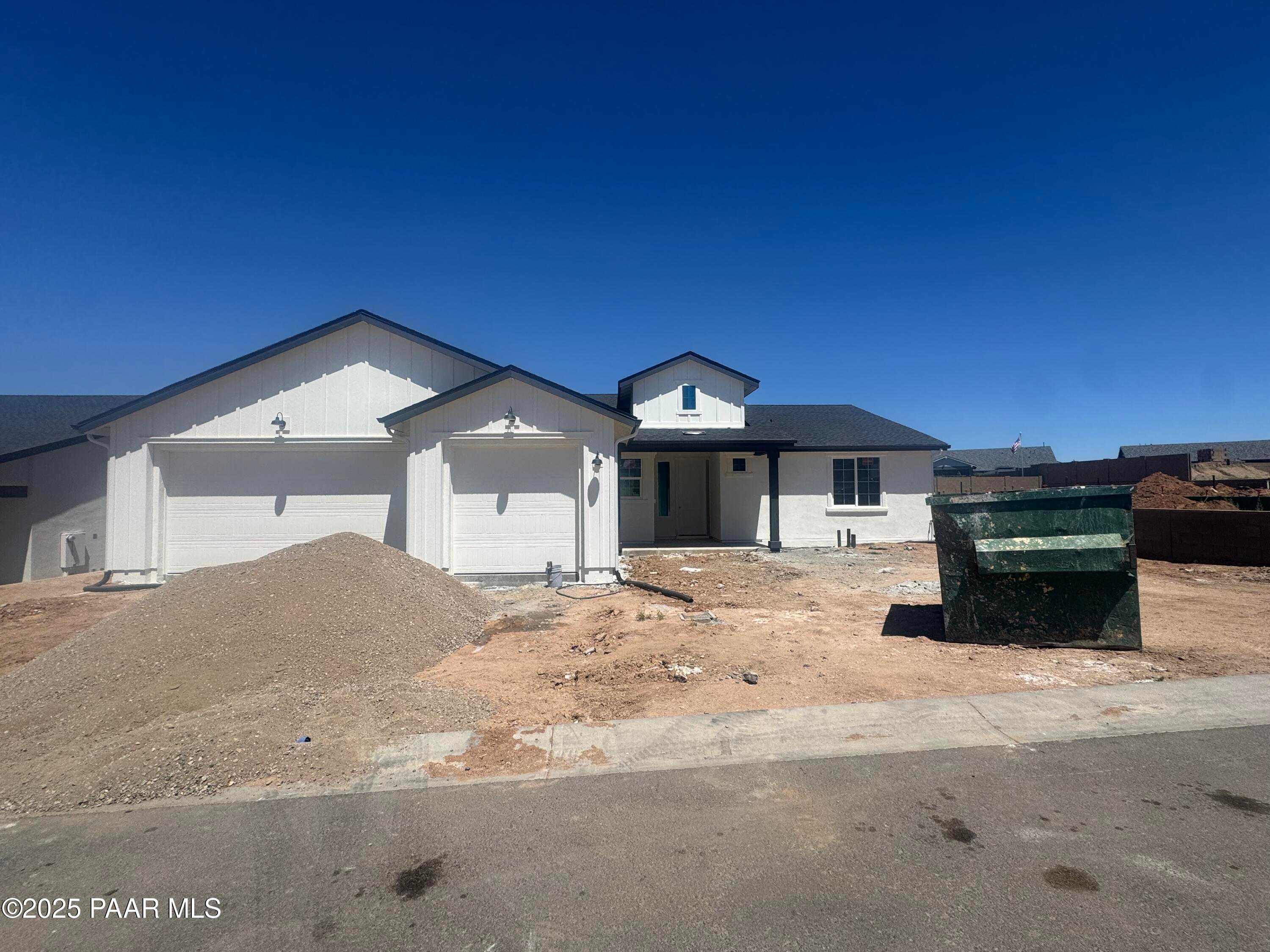 Modern single-story white home with 3-car garage, black trim, and construction site in Westwood, Prescott, Arizona by Davidson Homes