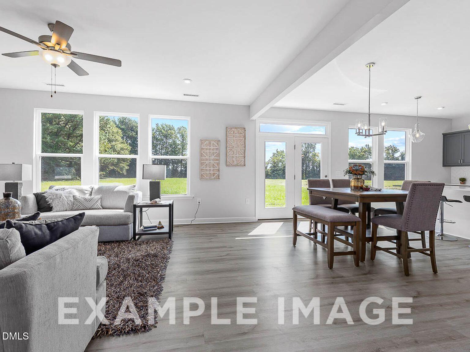 Open-concept living dining area with gray sofa, wood table, French doors to patio in Chestnut B home, Lillington, NC