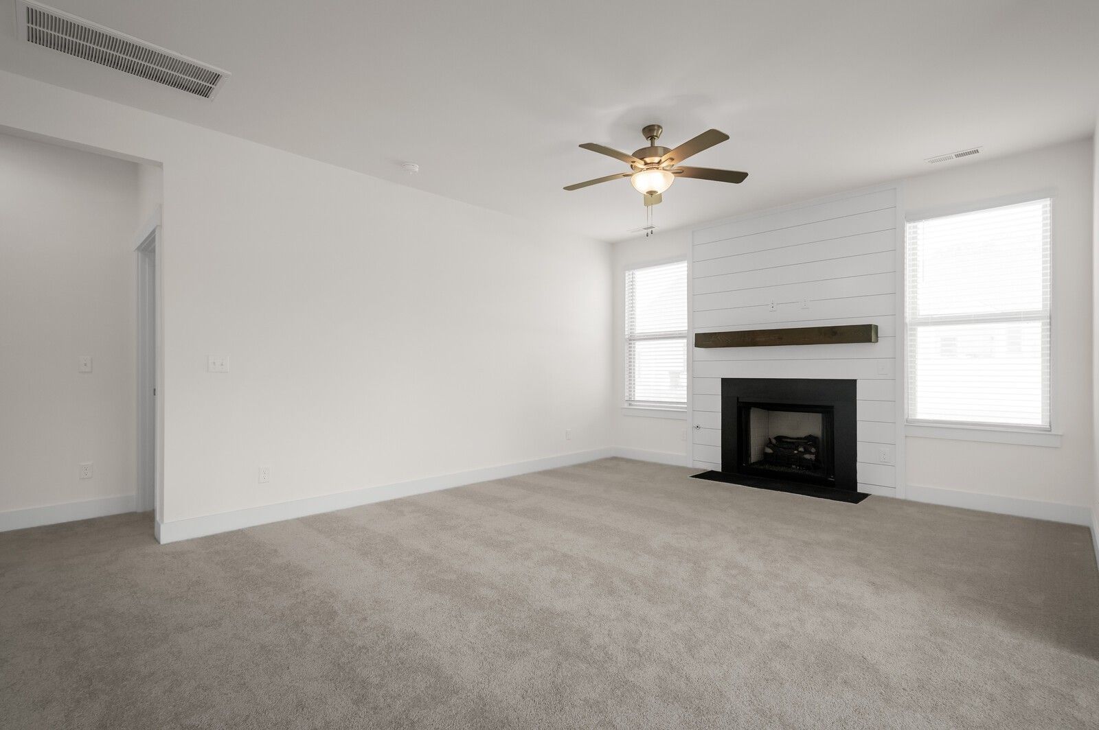 Living room with fireplace, shiplap accent wall, and ceiling fan in The Ash A floor plan at Woods Crossing, Gallatin, TN.