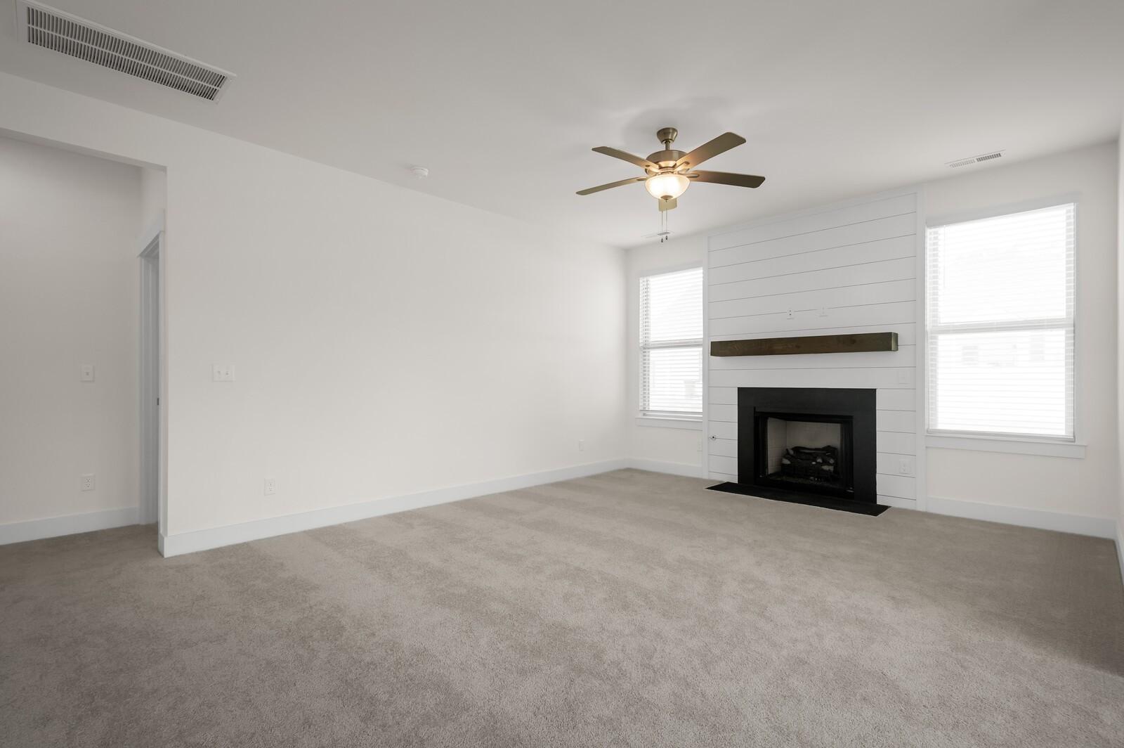 Living room with fireplace, shiplap accent wall, and ceiling fan in The Ash A floor plan at Woods Crossing, Gallatin, TN.