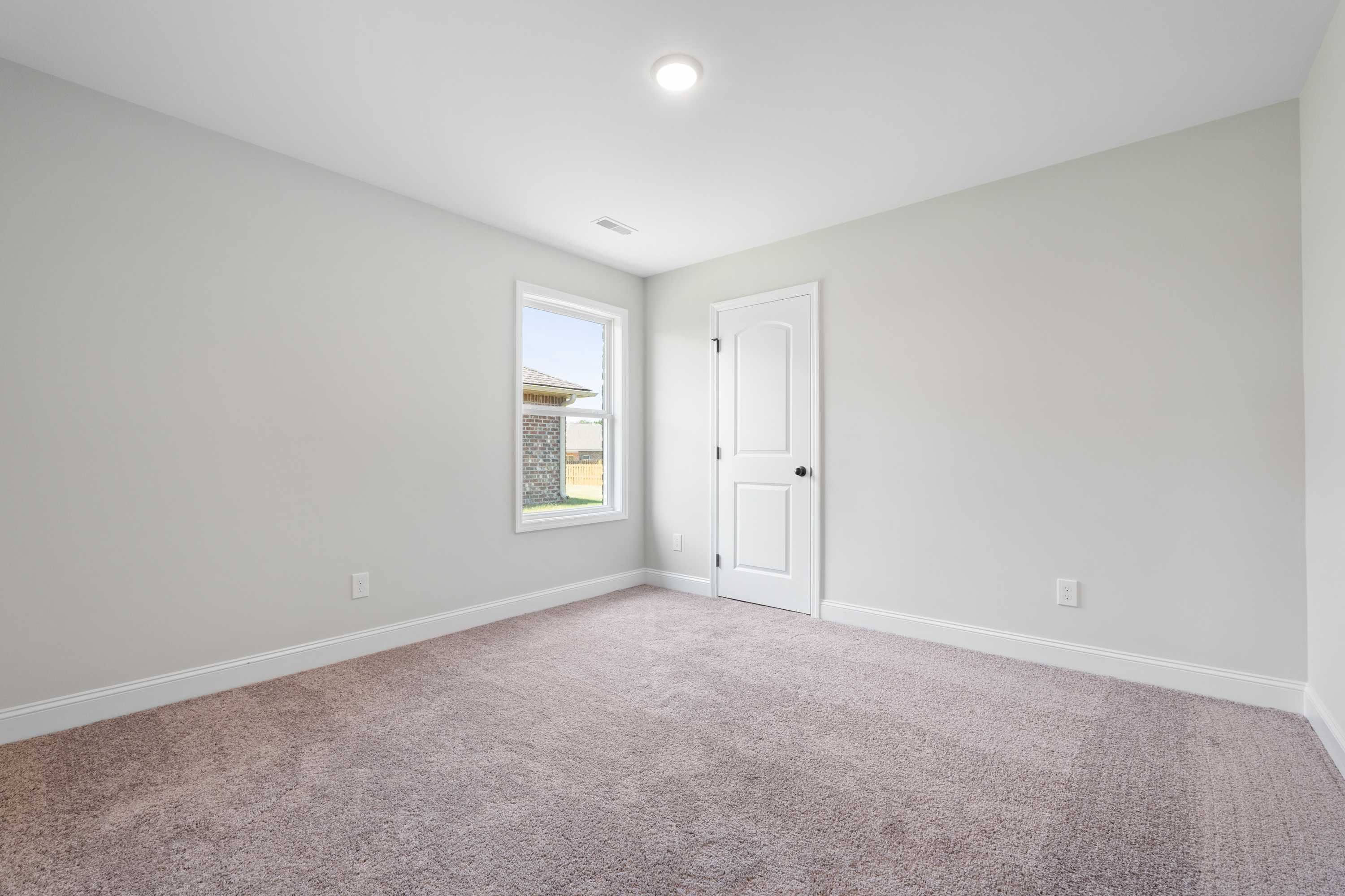 Spacious secondary bedroom in The Everett C with light gray walls, beige carpet, large window, and white door