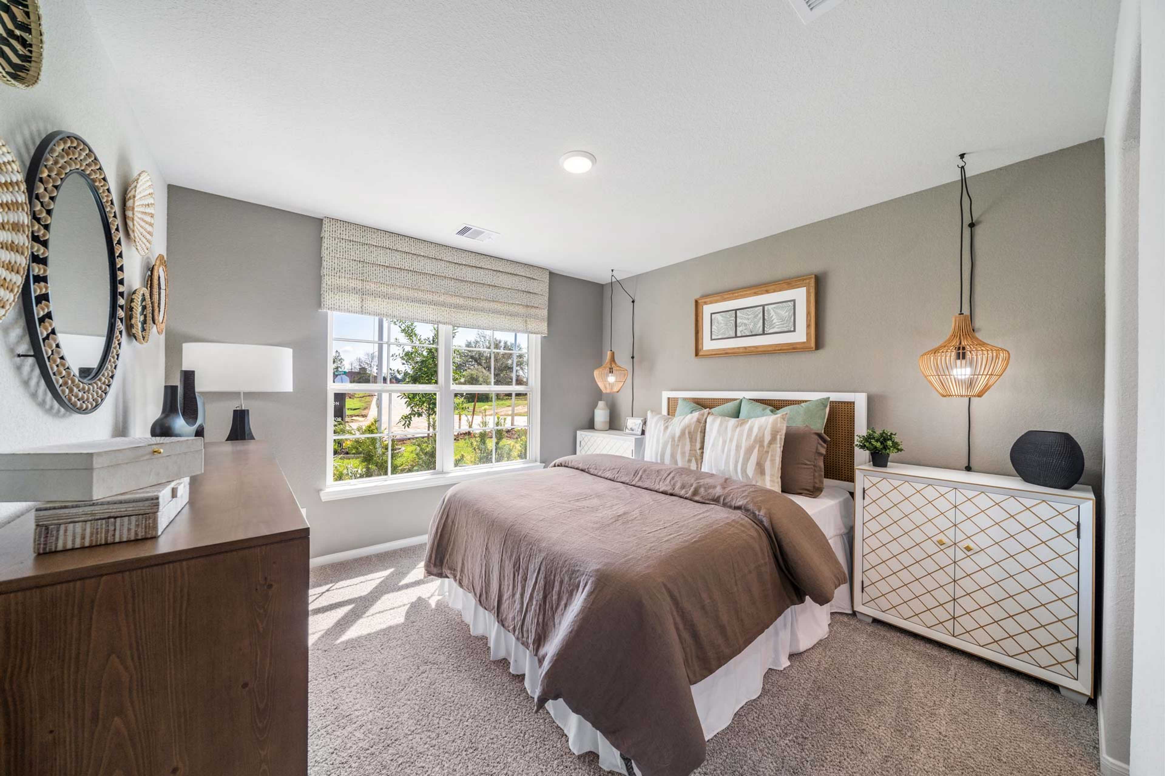 Cozy bedroom interior at Windmill Estates in Magnolia Texas featuring queen bed, rattan mirrors, pendant lights, and garden view window