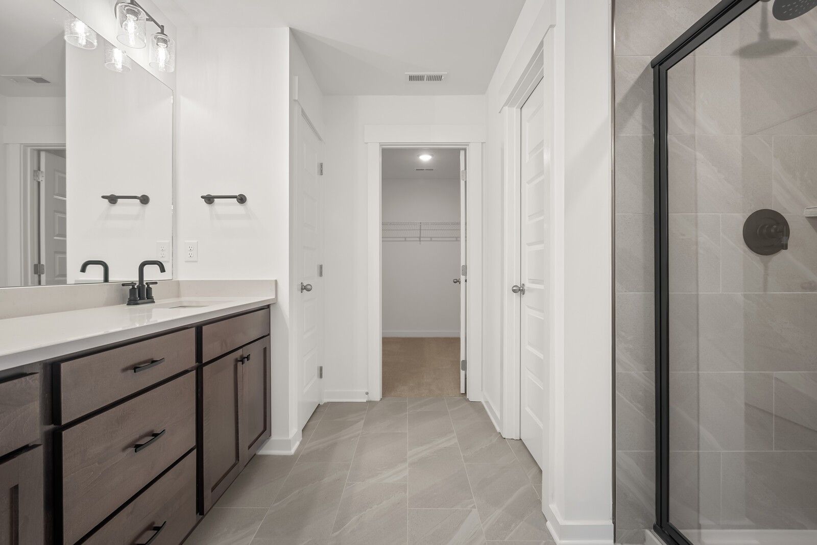 Modern master bathroom with double vanity, shaker cabinets, walk-in closet, and frameless glass shower in Davidson Homes The Logan C, Gallatin, TN