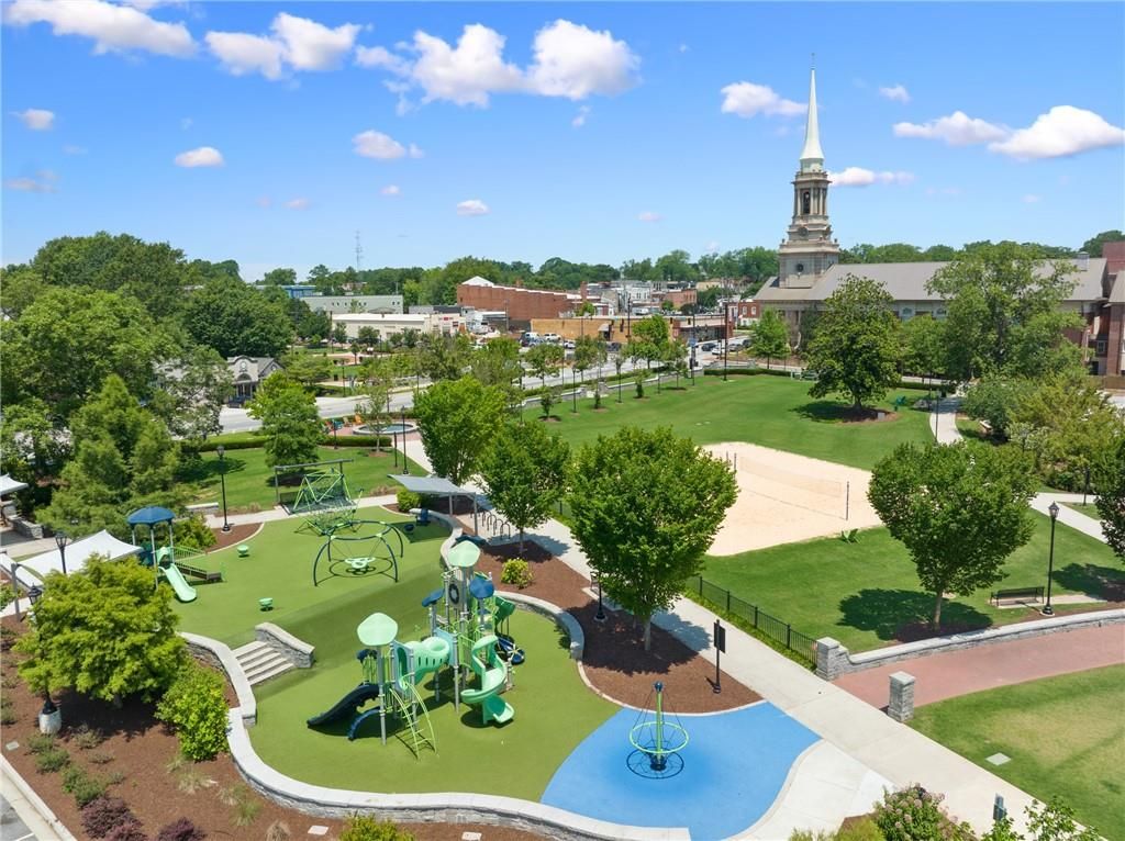 Vibrant community playground with green slides, swings, and splash pad amid trees in Kelly Preserve, Loganville, Georgia