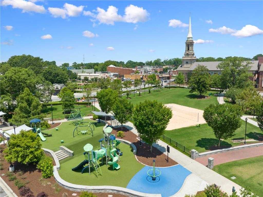 Vibrant community park with colorful playground equipment, green fields, trees, and church steeple in Kelly Preserve, Loganville, Georgia