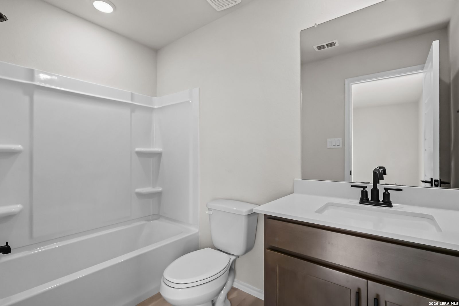 Modern bathroom with tub-shower combo and dark wood vanity in The Douglas C floor plan at Hannah Heights, Seguin, Texas.