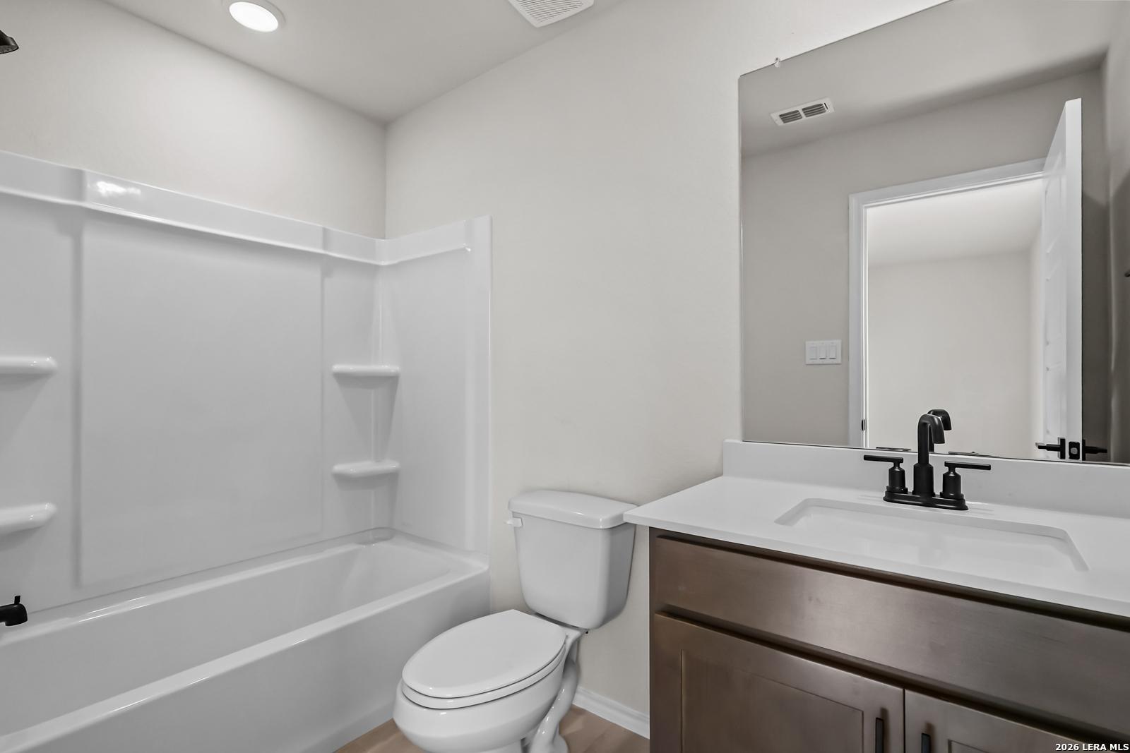 Modern bathroom with tub-shower combo and dark wood vanity in The Douglas C floor plan at Hannah Heights, Seguin, Texas.