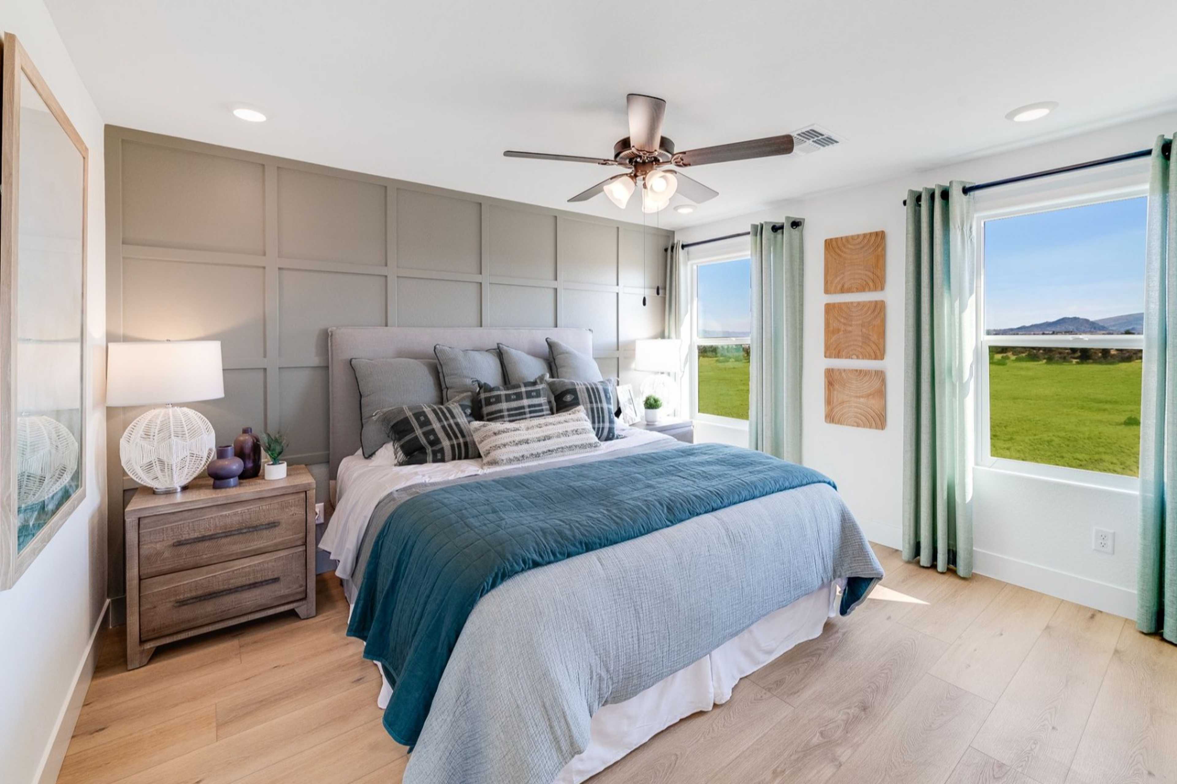 Spacious master bedroom in The Wilmington with king bed, mountain view windows, ceiling fan, neutral walls, and hardwood floors in Prescott, AZ