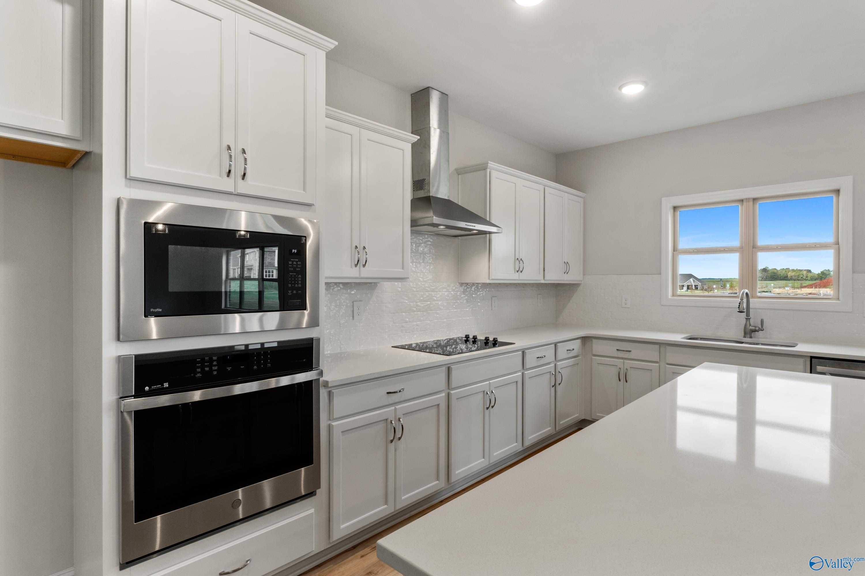 Modern white kitchen with stainless steel oven, microwave, and island in Davidson Homes The Chelsea C, Harvest, Alabama