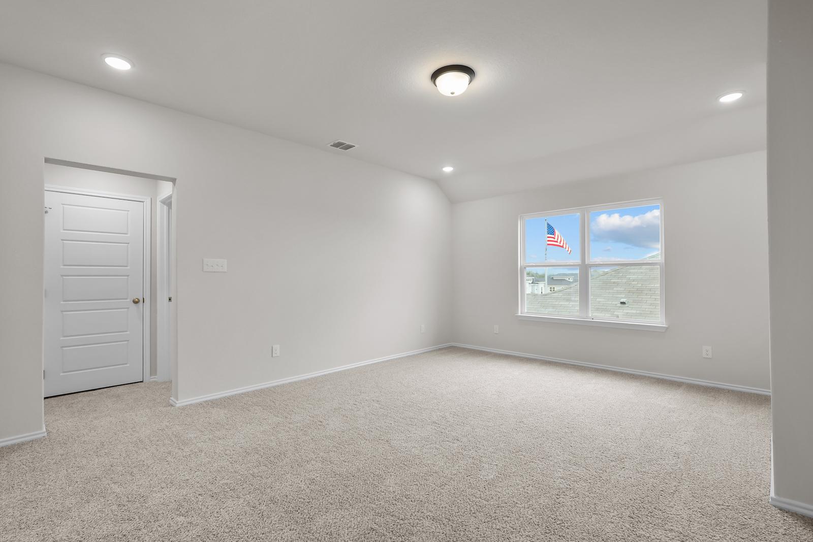 Spacious bedroom interior in The Sequoia C featuring neutral carpeting, recessed lighting, and large windows.