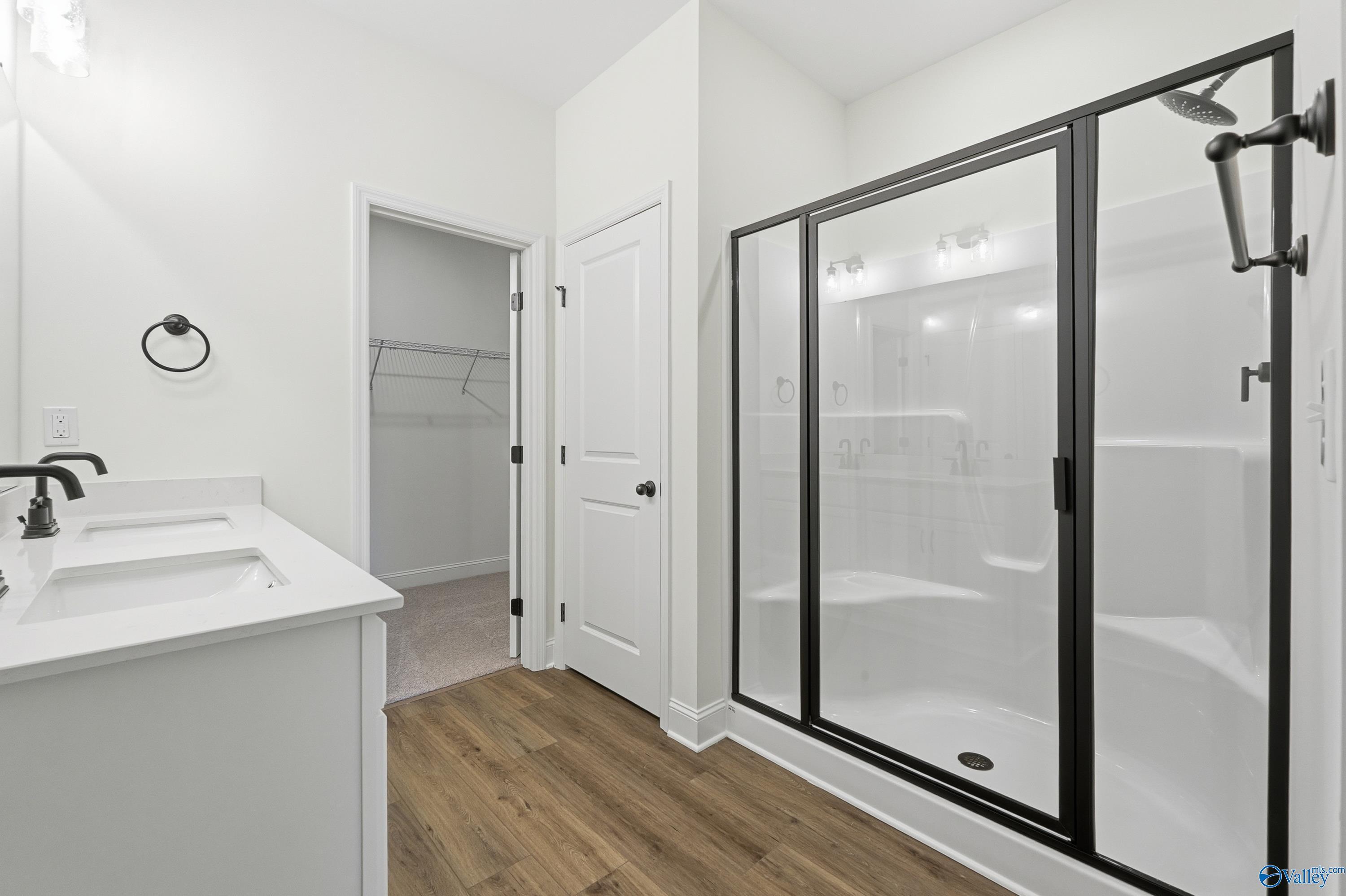 Modern master bathroom with double white vanity and black-framed glass shower in Davidson Homes The Franklin C, New Market, Alabama