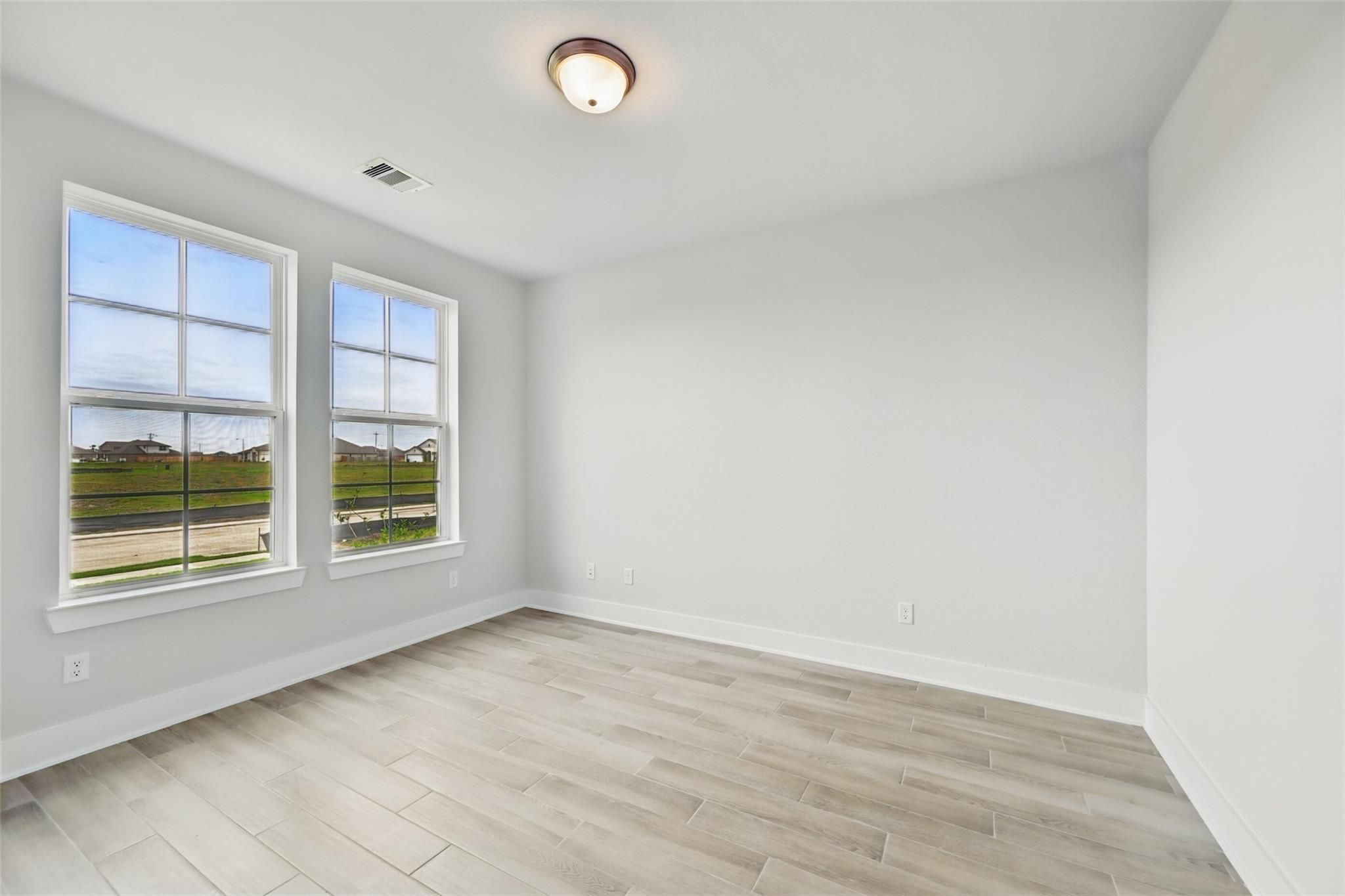 Bright secondary bedroom with large windows and light wood flooring in Davidson Homes The Philip A, Lago Mar, Texas City