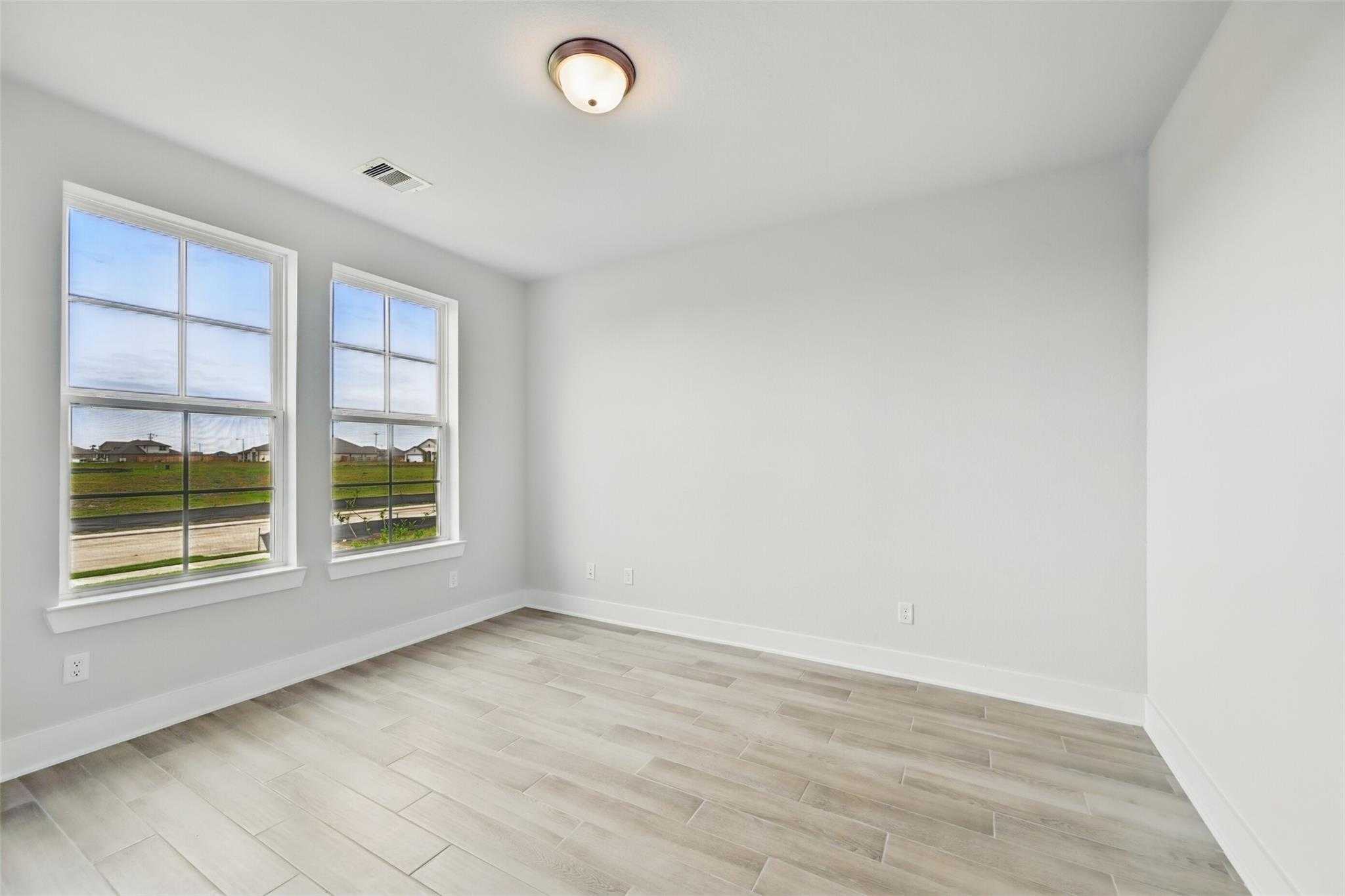 Bright secondary bedroom with large windows and light wood flooring in Davidson Homes The Philip A, Lago Mar, Texas City