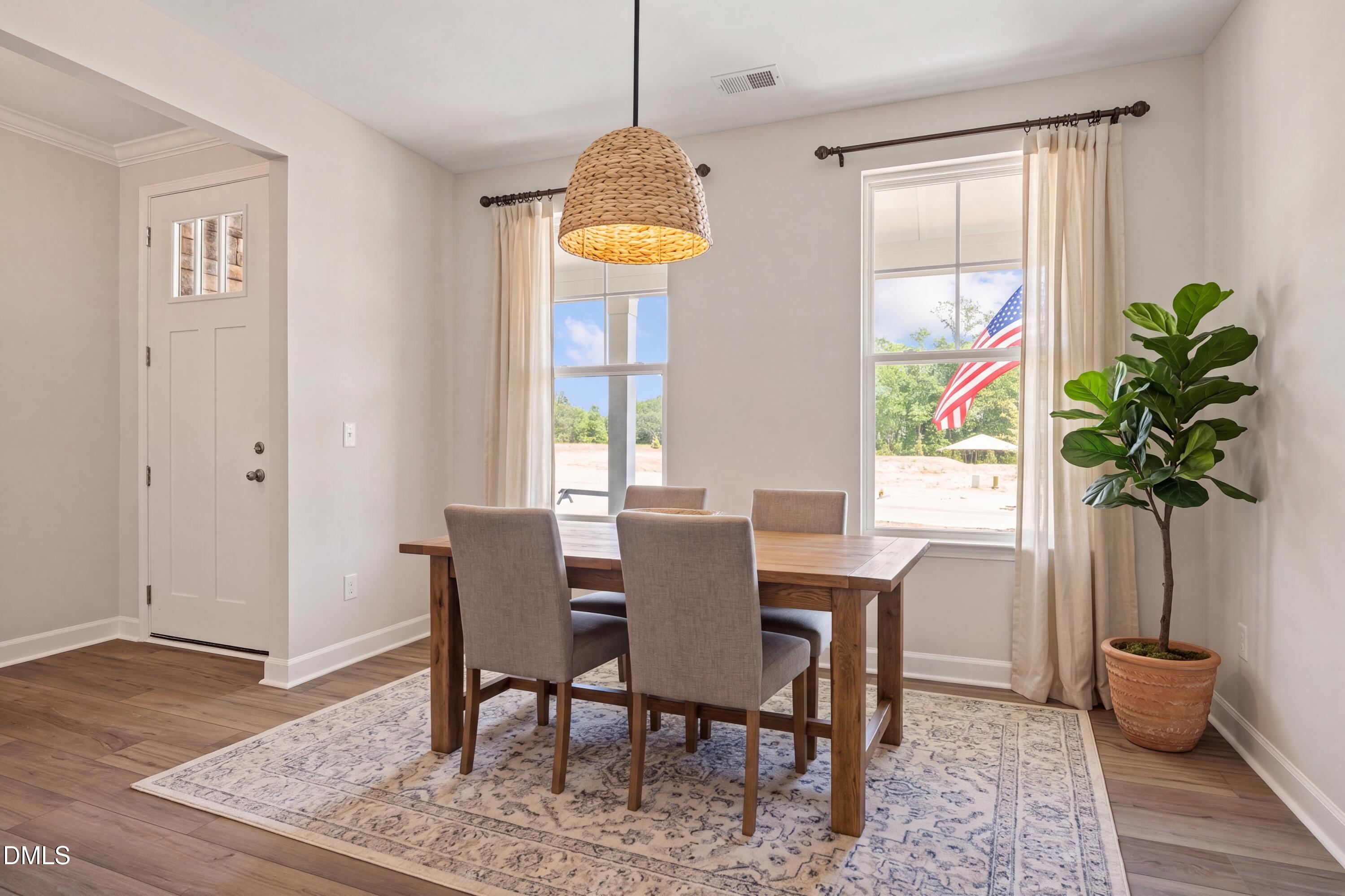 Bright dining area with wooden table, woven pendant light, and large windows in The Willow D floor plan at Wendell Ridge.