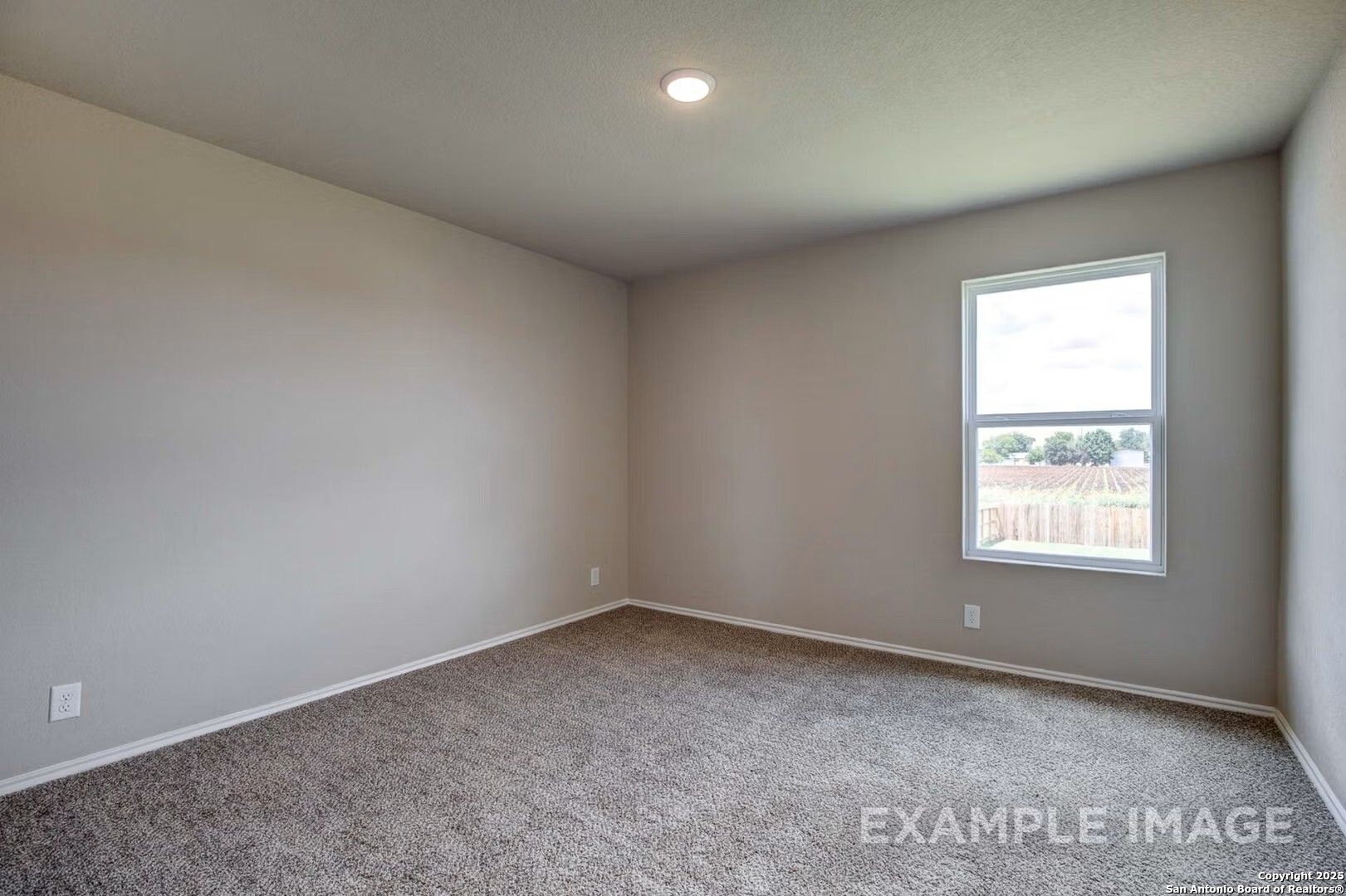 Spacious empty bedroom with neutral gray walls, plush carpet, and large window in Davidson Homes The Murray K, San Antonio