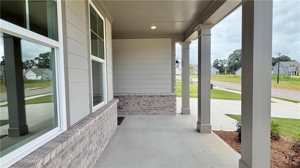 Covered front porch with brick accents at The Hickory C floor plan by Davidson Homes in Wehunt Meadows, Hoschton, Georgia.